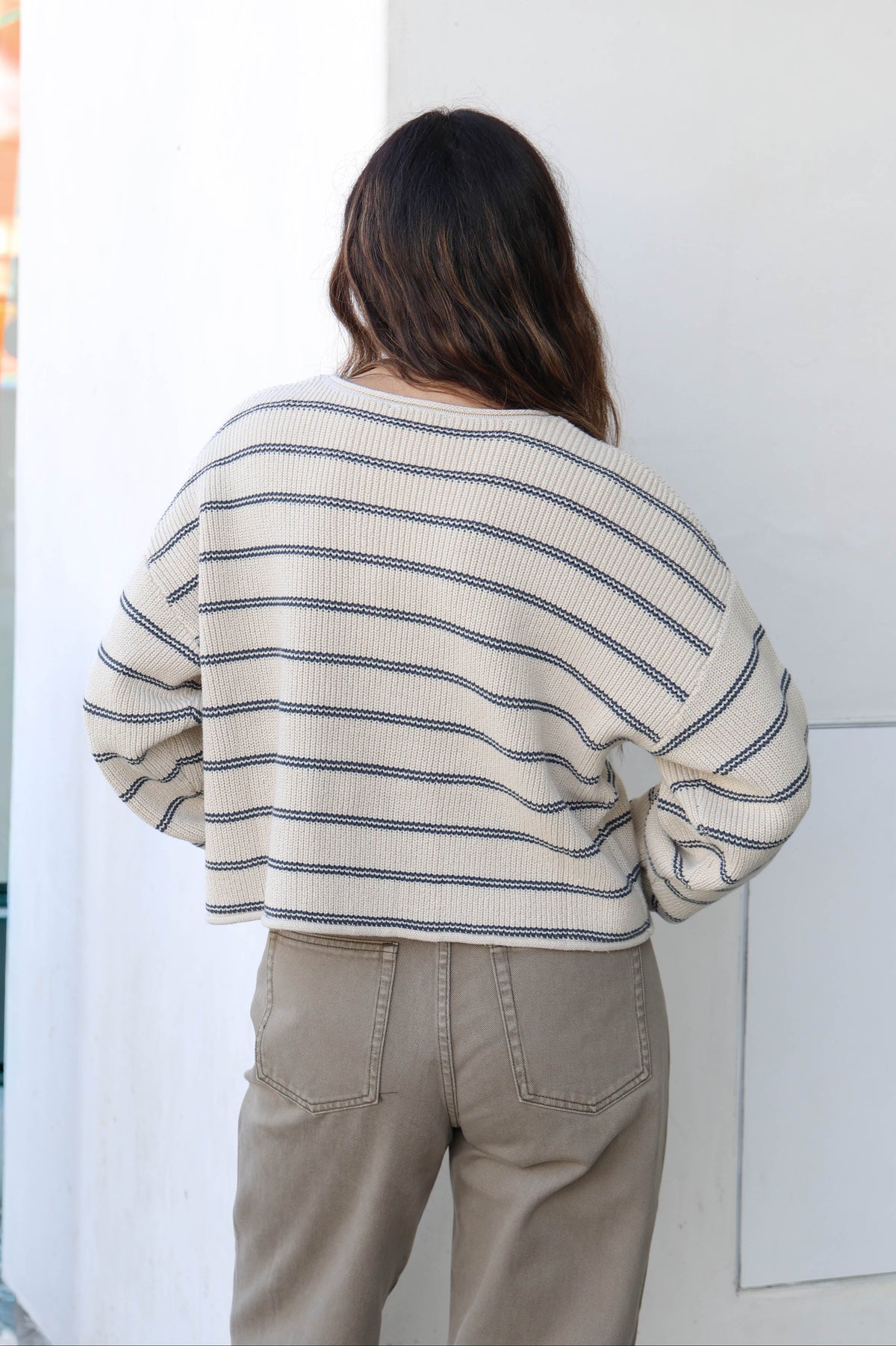 Woman wearing a striped sweater, olive pants and sunglasses.