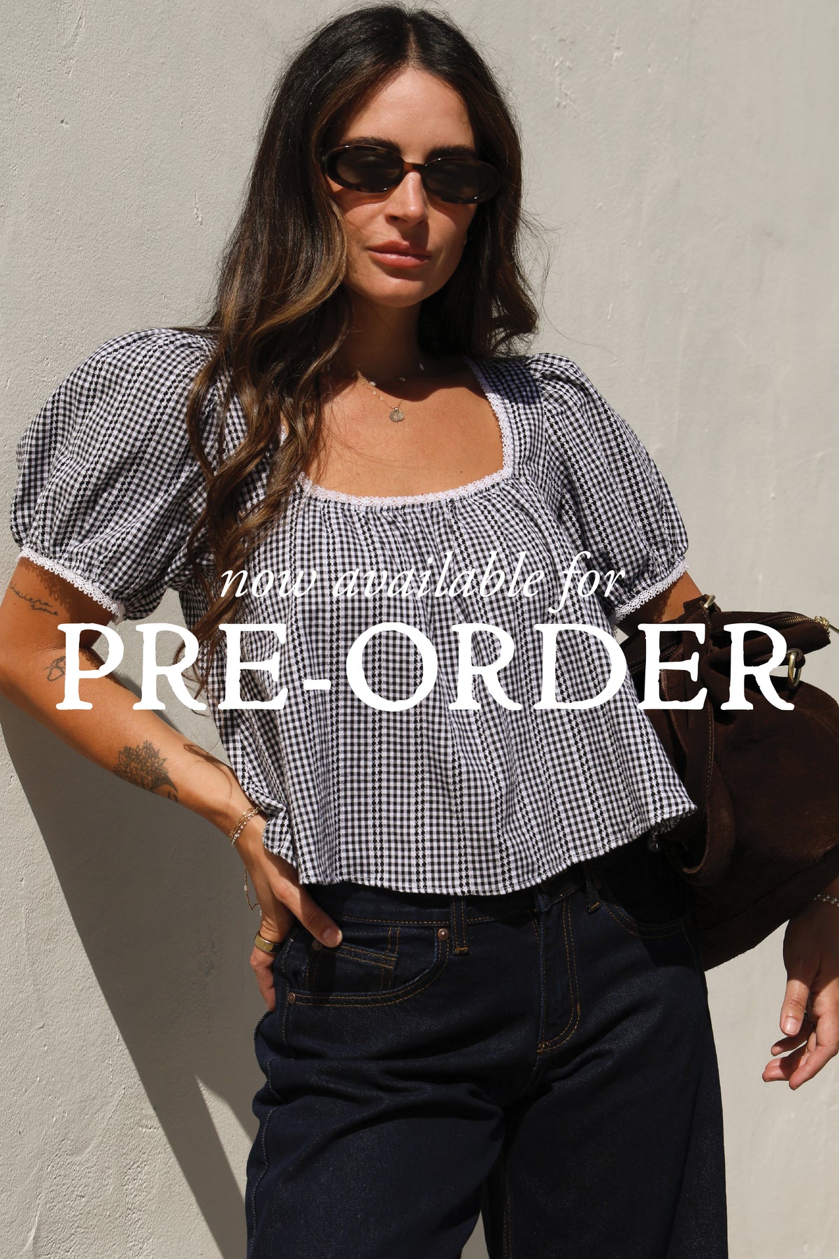 "Now available for Pre-Order" text across the image. Woman wearing a gingham top and jeans against a white wall.