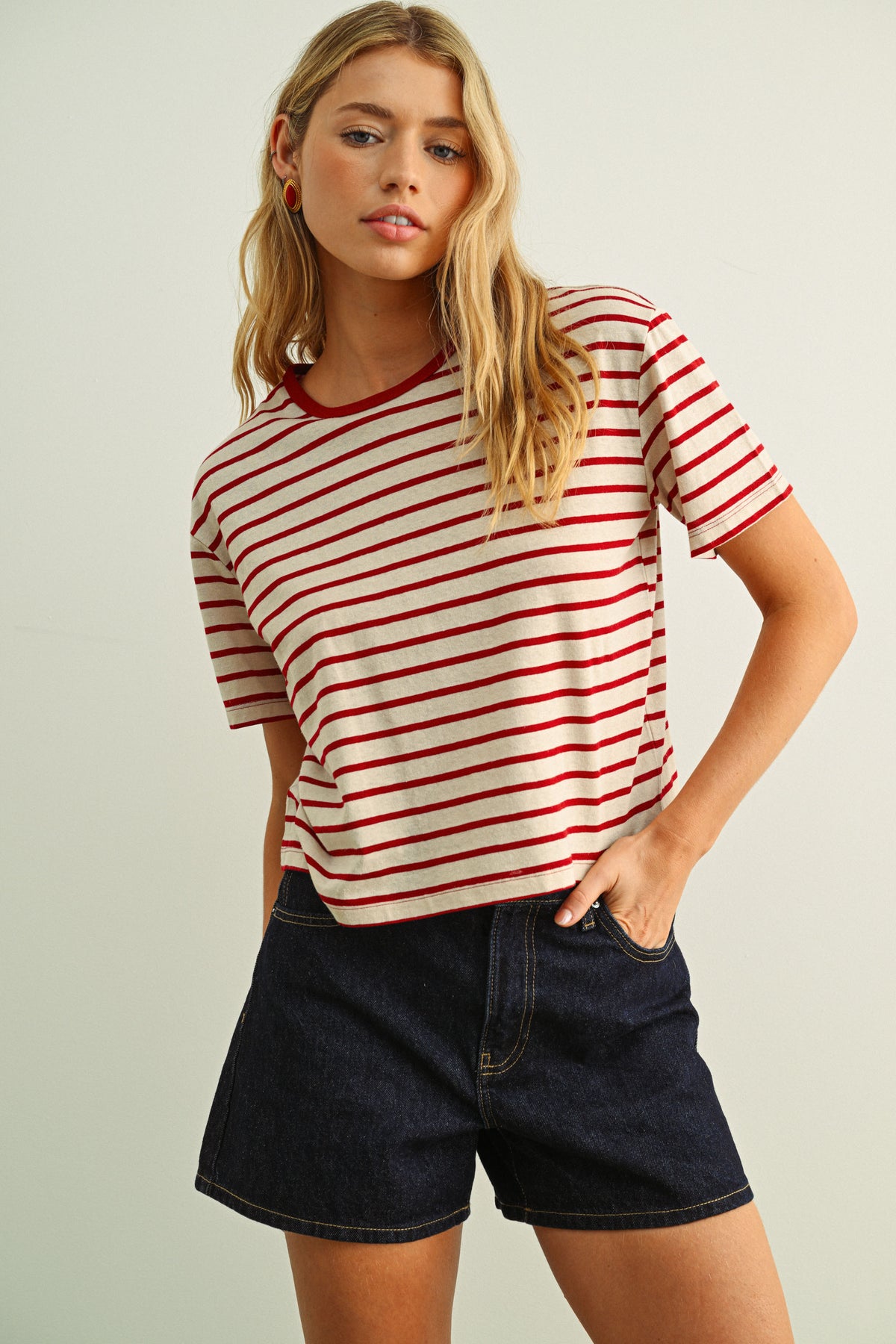 Woman wearing a red and white striped shirt with black shorts on a plain background