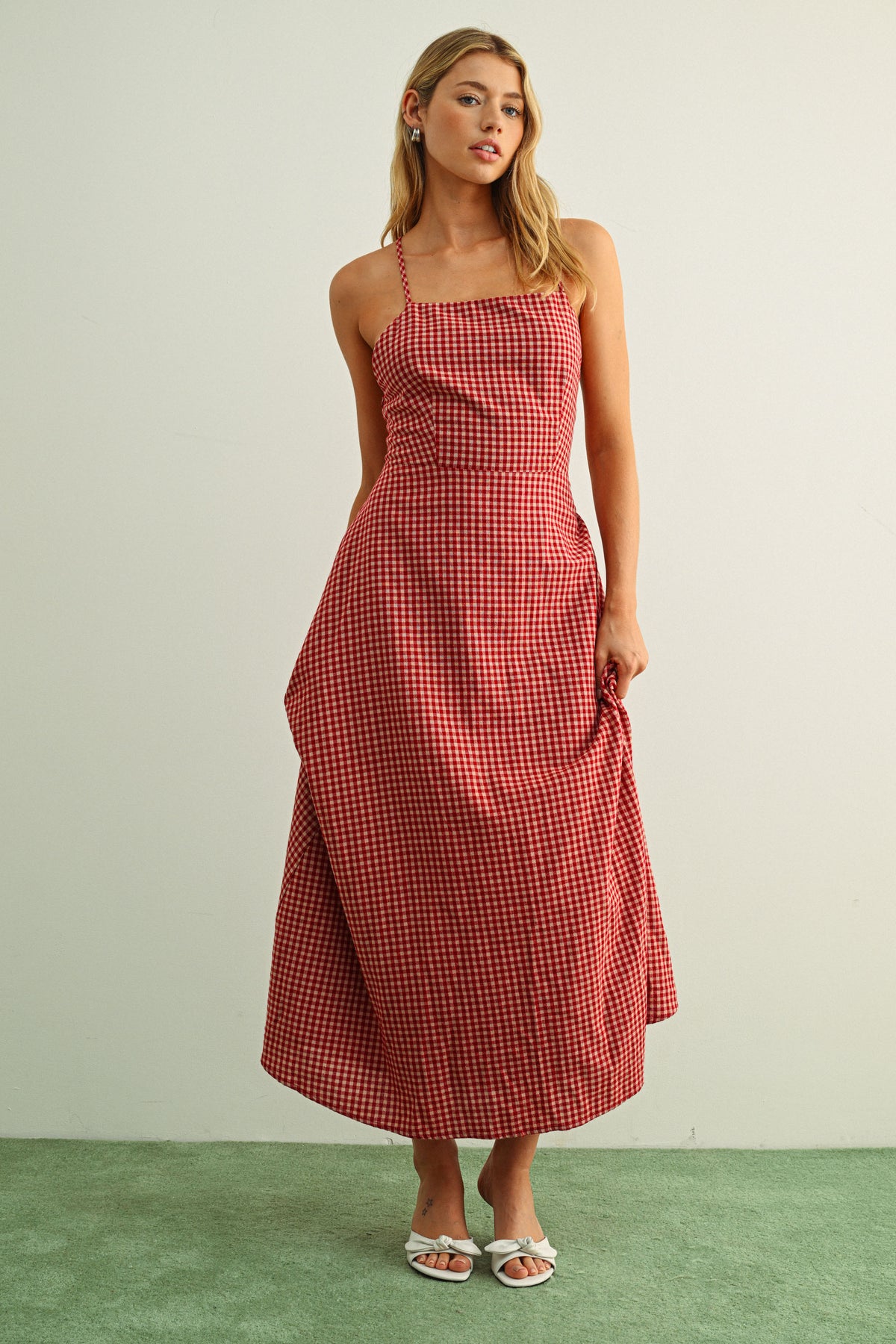 Woman wearing a red checkered dress against a plain background