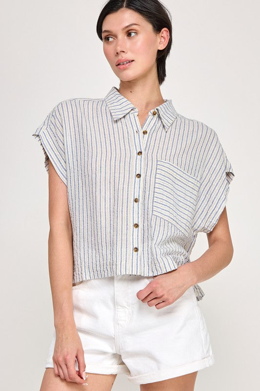 Woman wearing a striped shirt and white shorts on a plain background