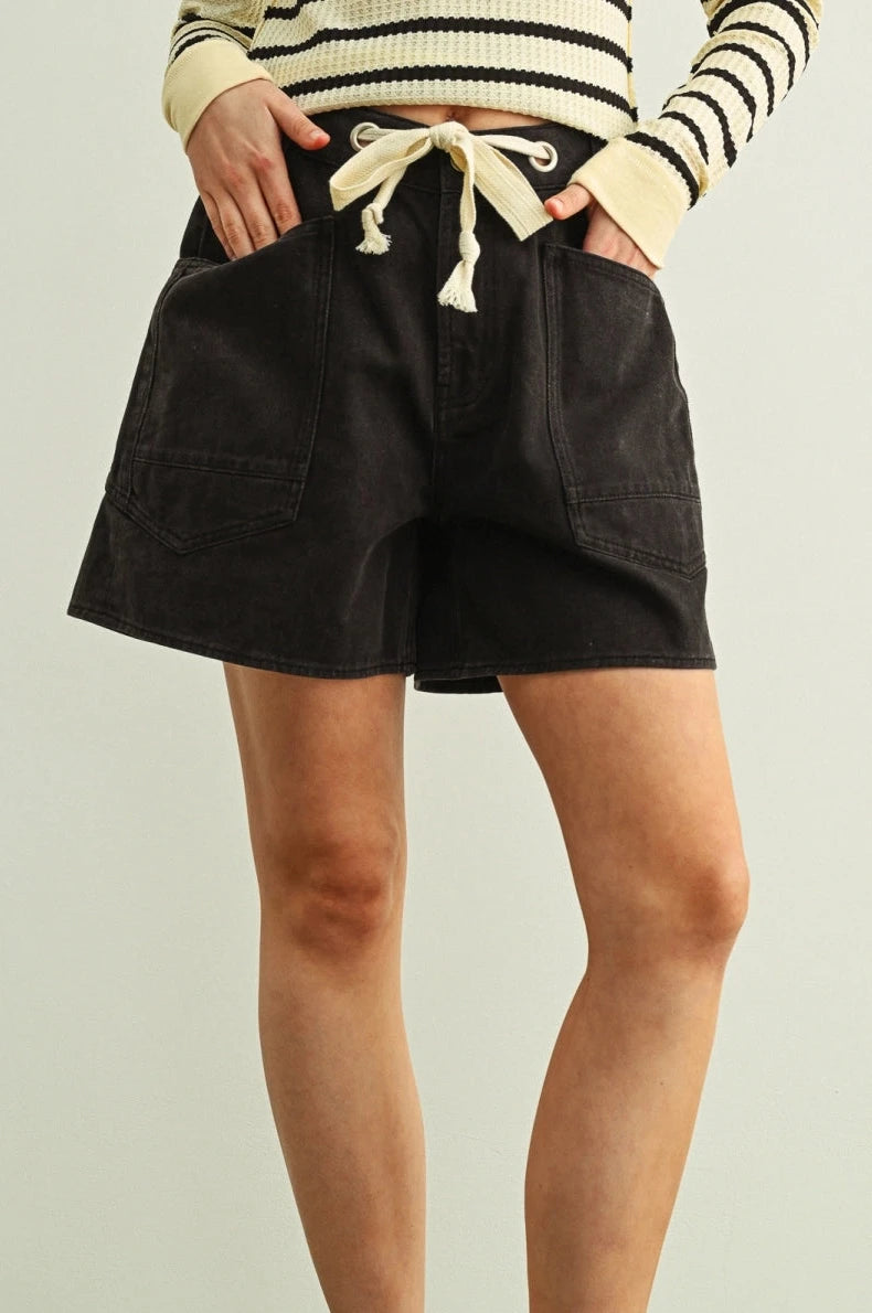 Person wearing black shorts and a striped sweater on a plain background
