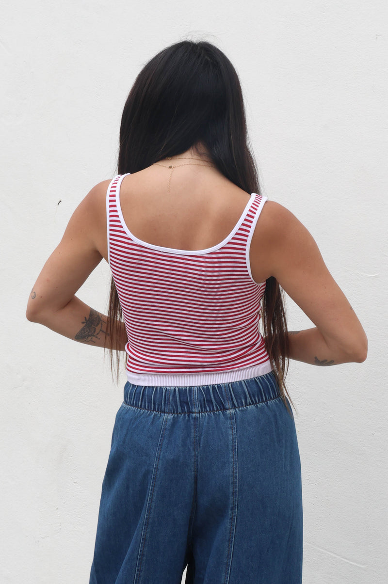 Person wearing a striped tank top and blue pants against a white background