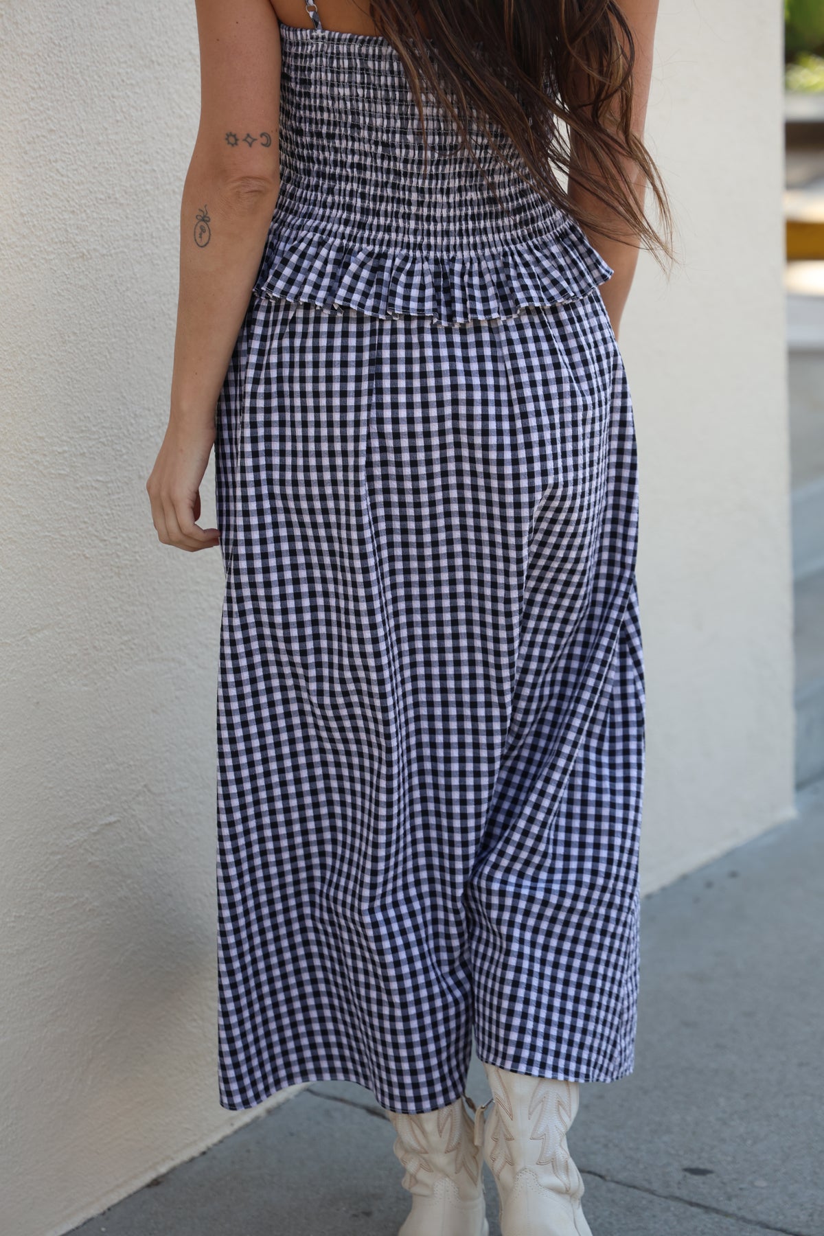 Person wearing a blue and white checkered dress with a plain background