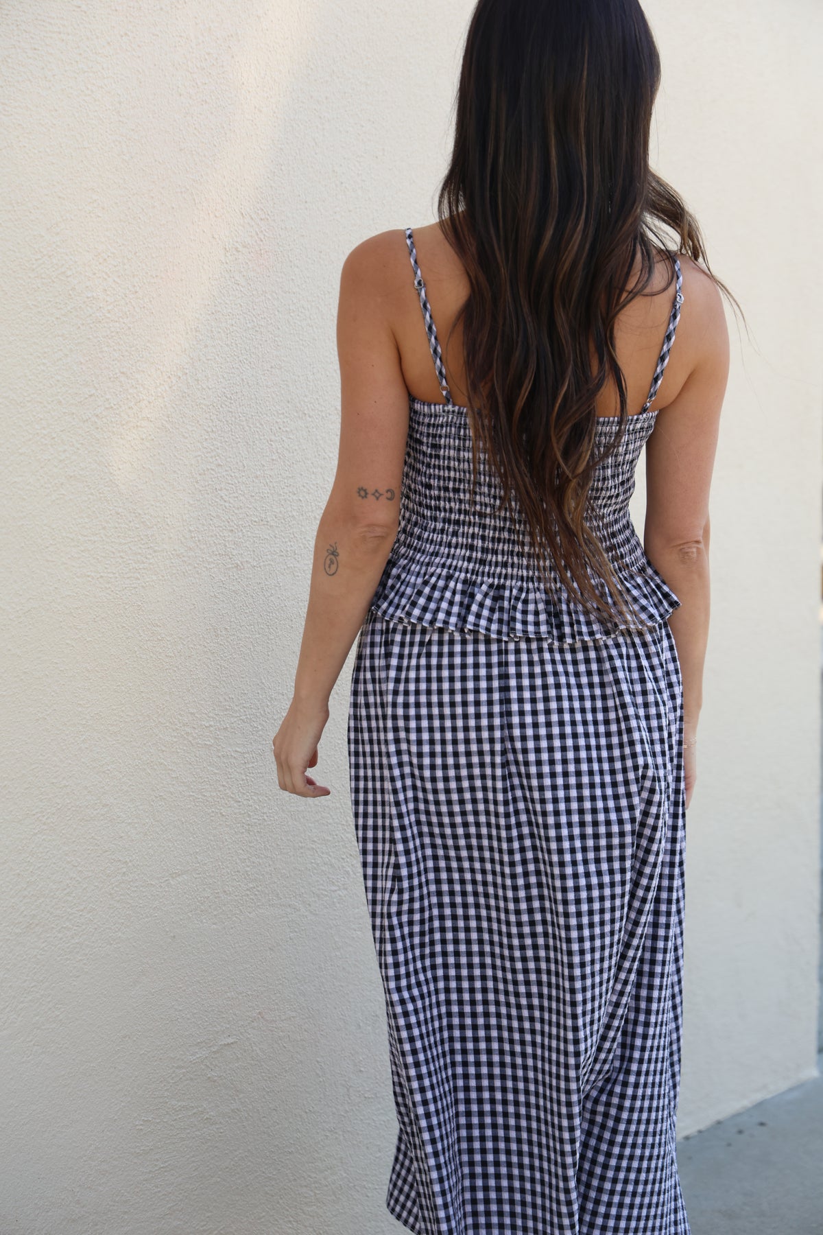 Person wearing a blue and white checkered dress against a plain background