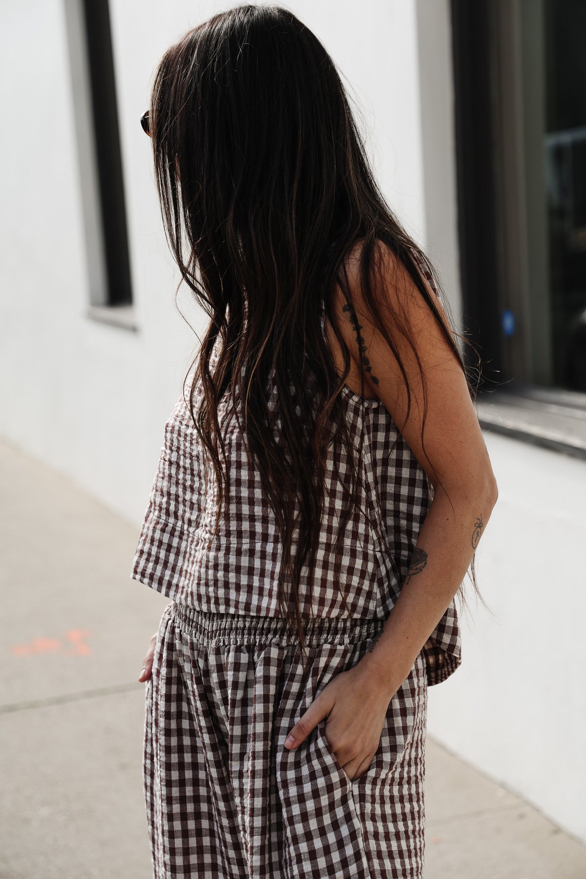 Person wearing a checkered outfit standing against a light-colored wall.