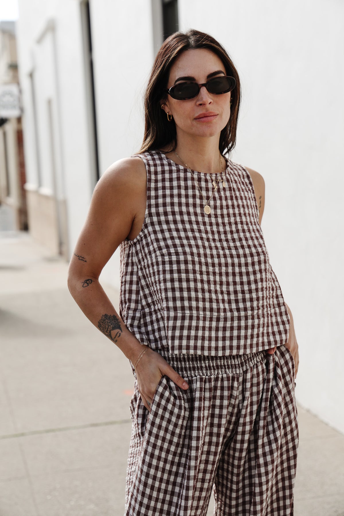 Woman wearing a checkered outfit with sunglasses on a city street.