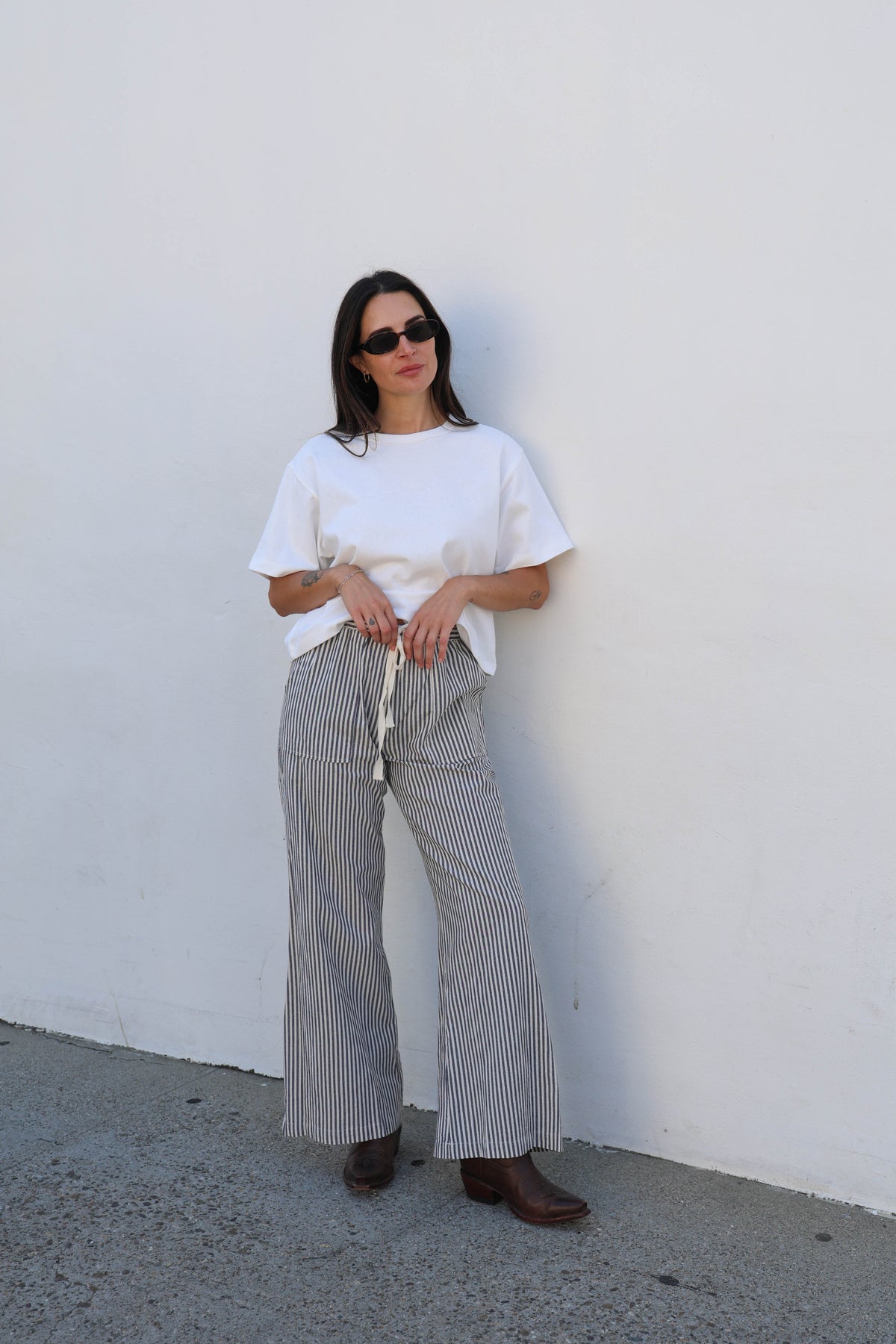 Woman wearing a white tee and striped pants against a white wall