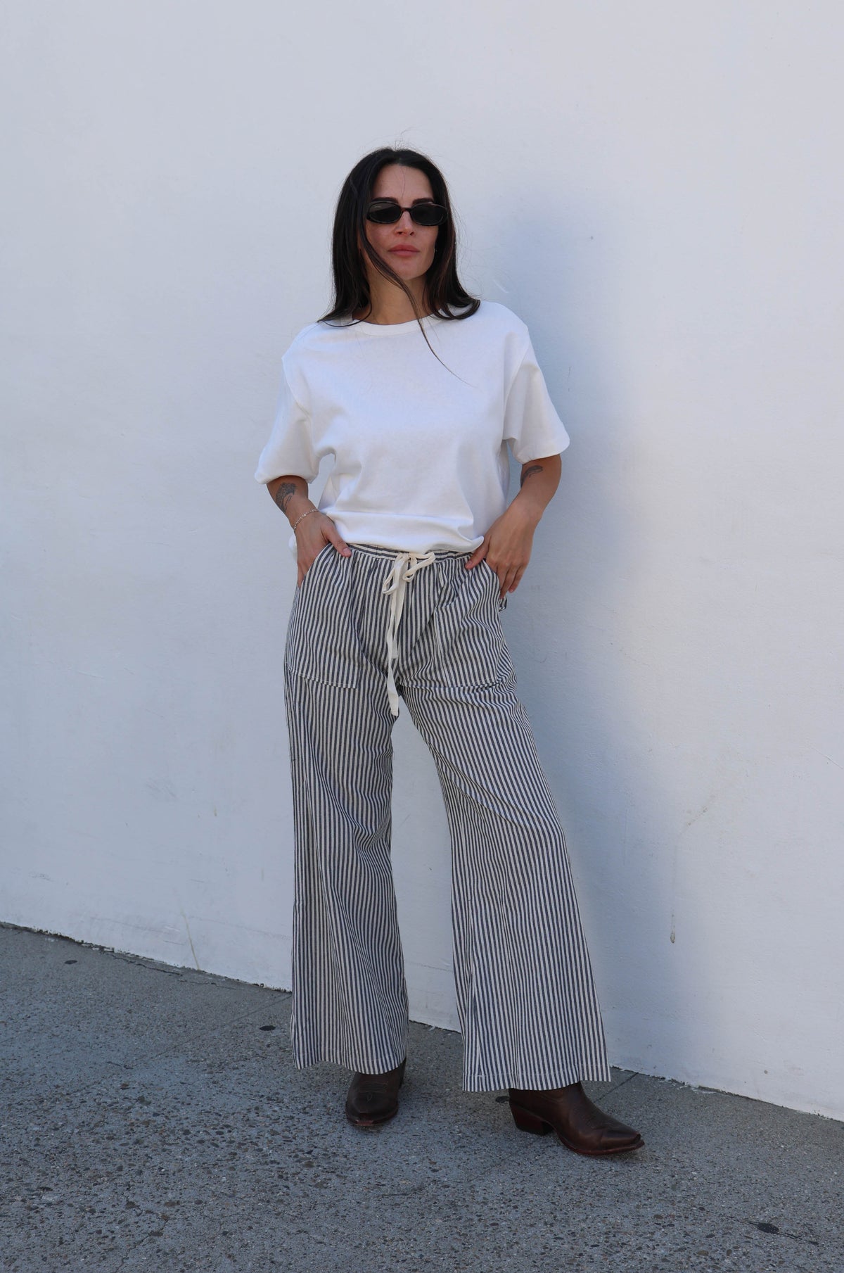 Person wearing a white top and striped pants against a plain background