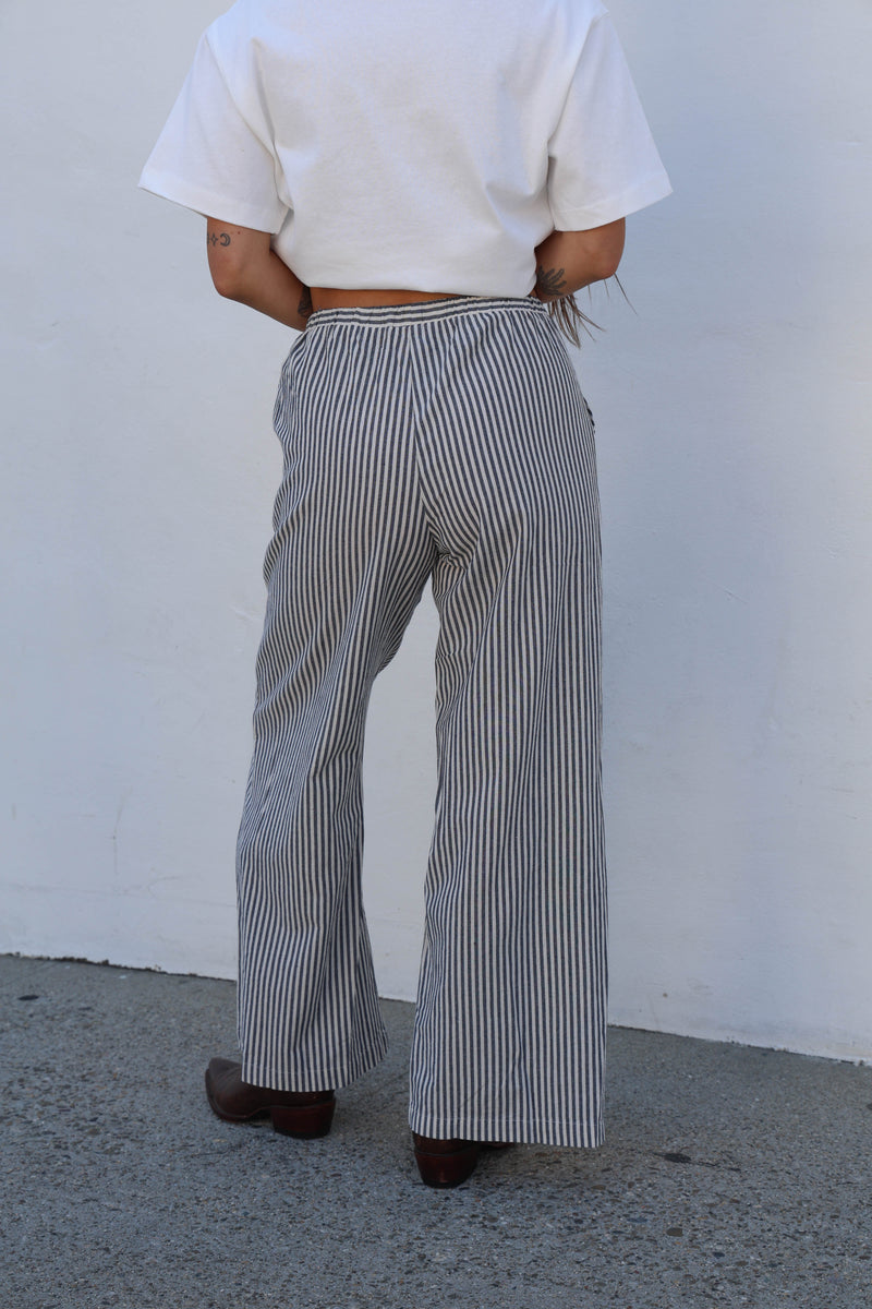Person wearing a white top and striped pants against a plain background