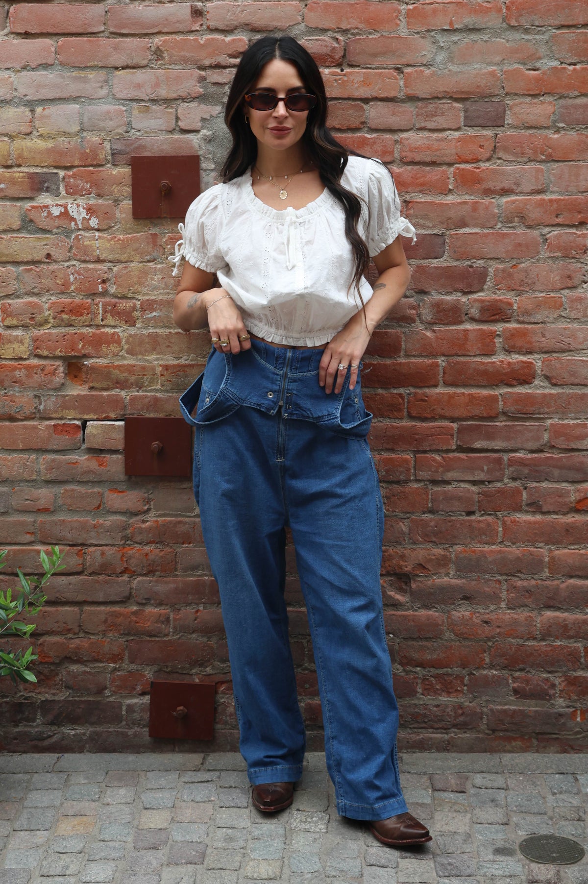 Woman wearing a white blouse against a brick background