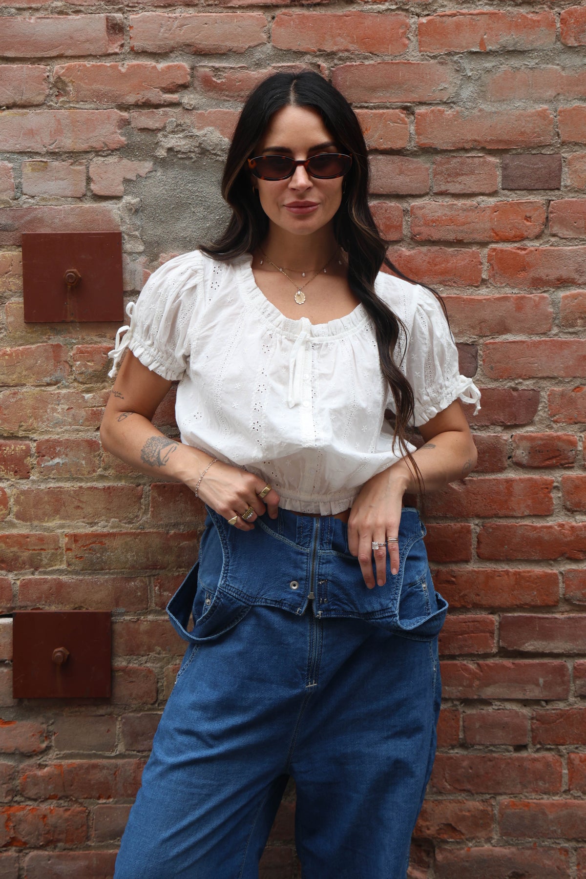 Woman wearing a white blouse against a brick background
