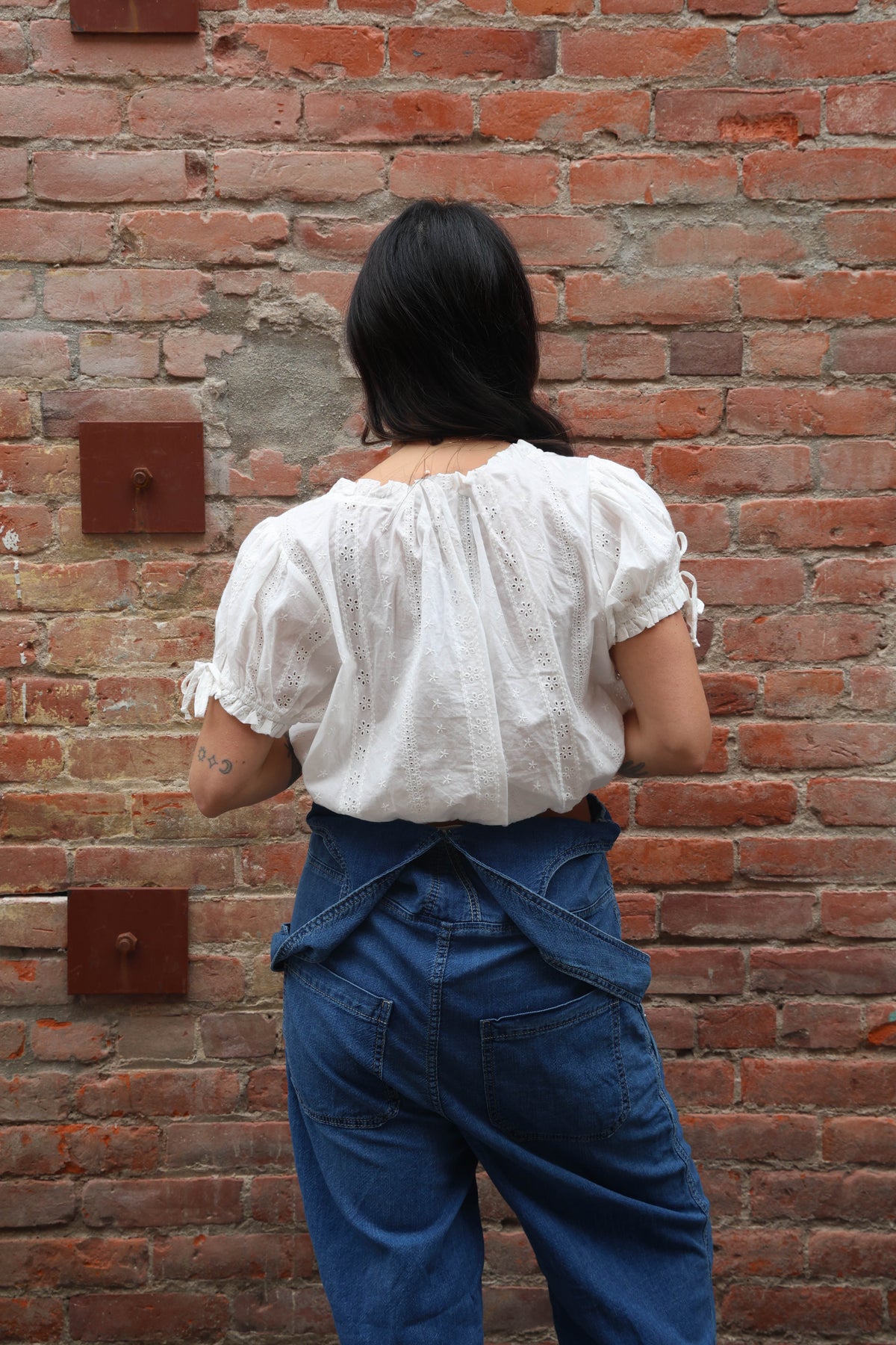 Woman wearing a white blouse against a brick background