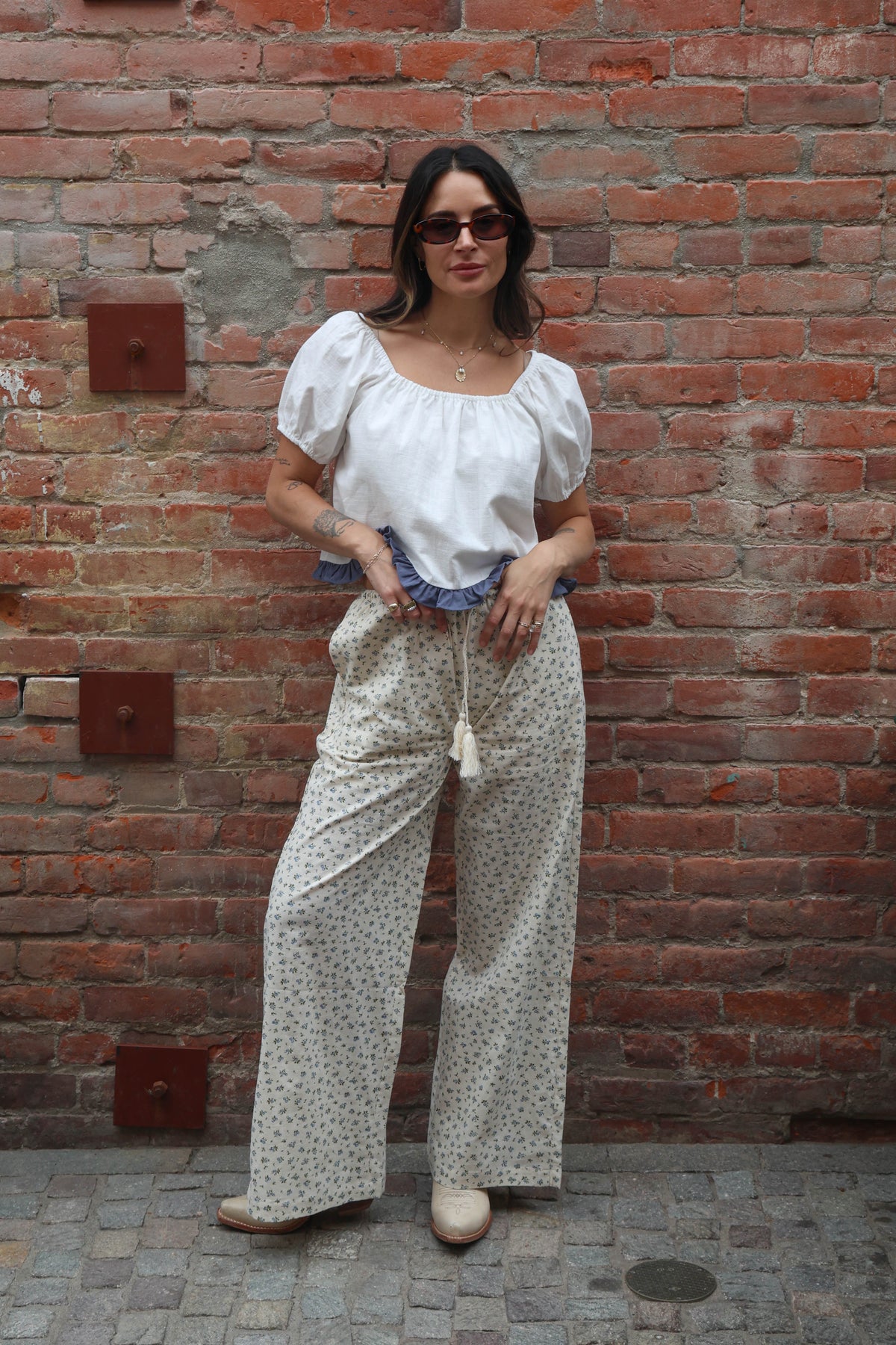 Woman wearing a white blouse against a brick background