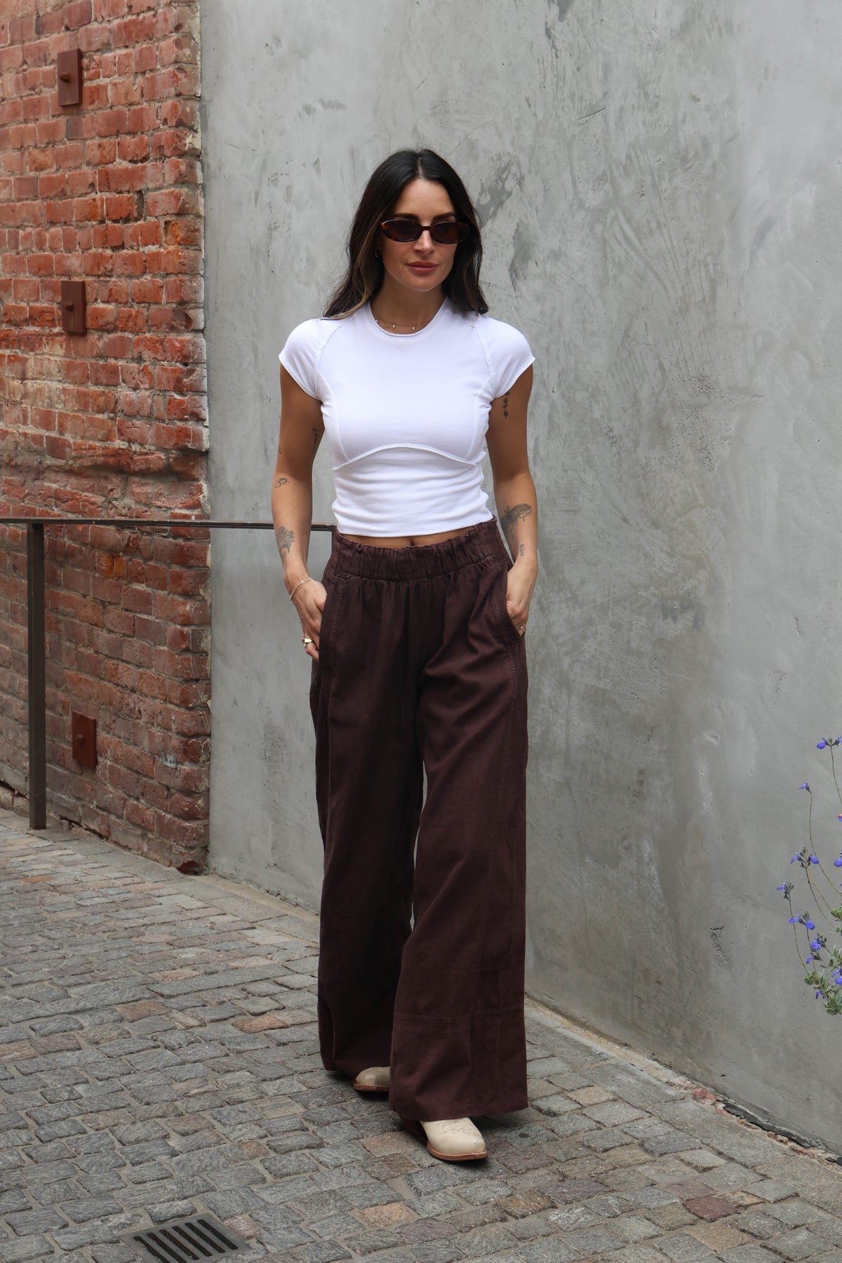 woman wearing brown linen pants against a grey background