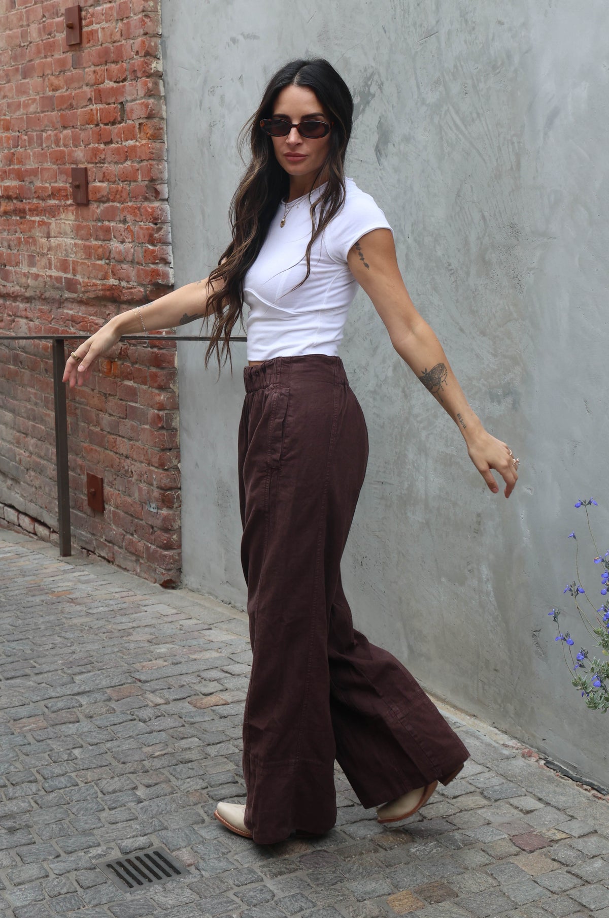 woman wearing brown linen pants against a grey background