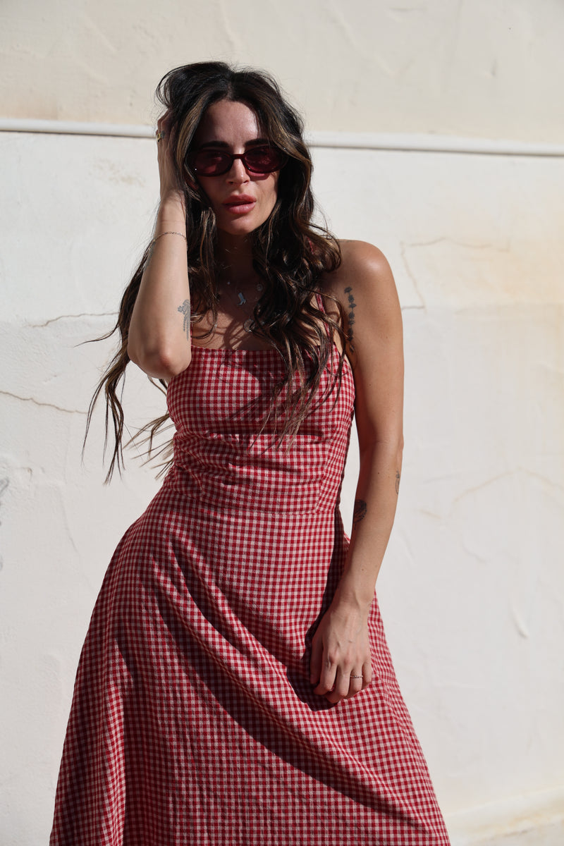 Woman wearing a red checkered dress lying on a white floor.