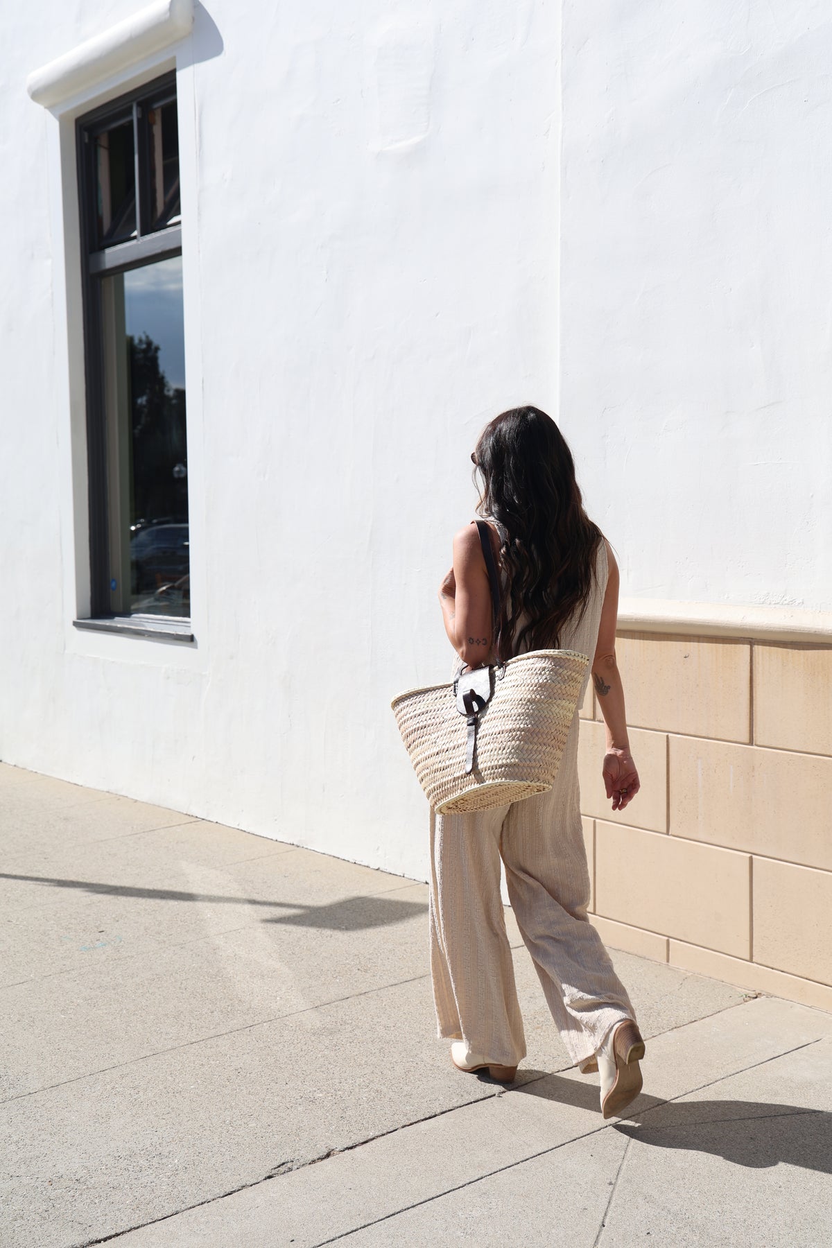 Person walking on a tiled floor with a white wall and window in the background