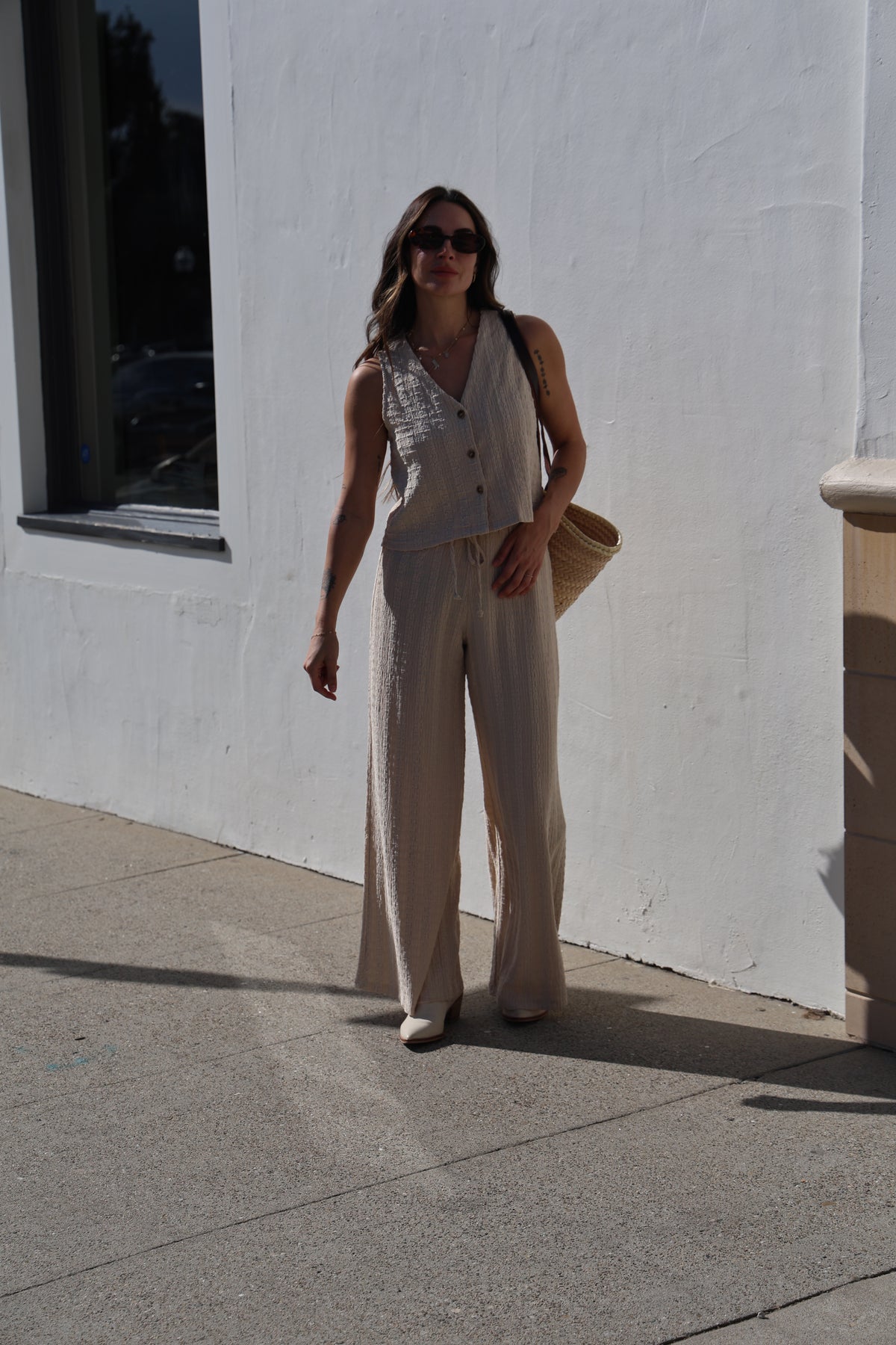 Woman in a white dress standing on a sidewalk with a building in the background
