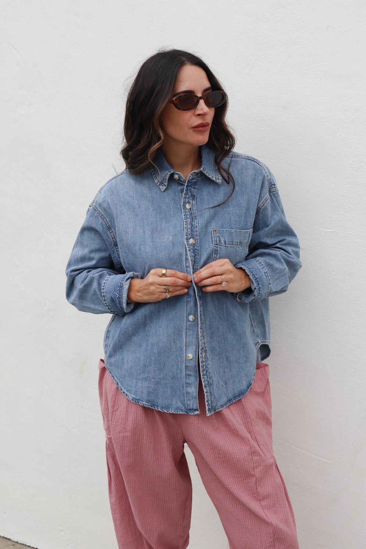Blue button up with pink pants against a white wall