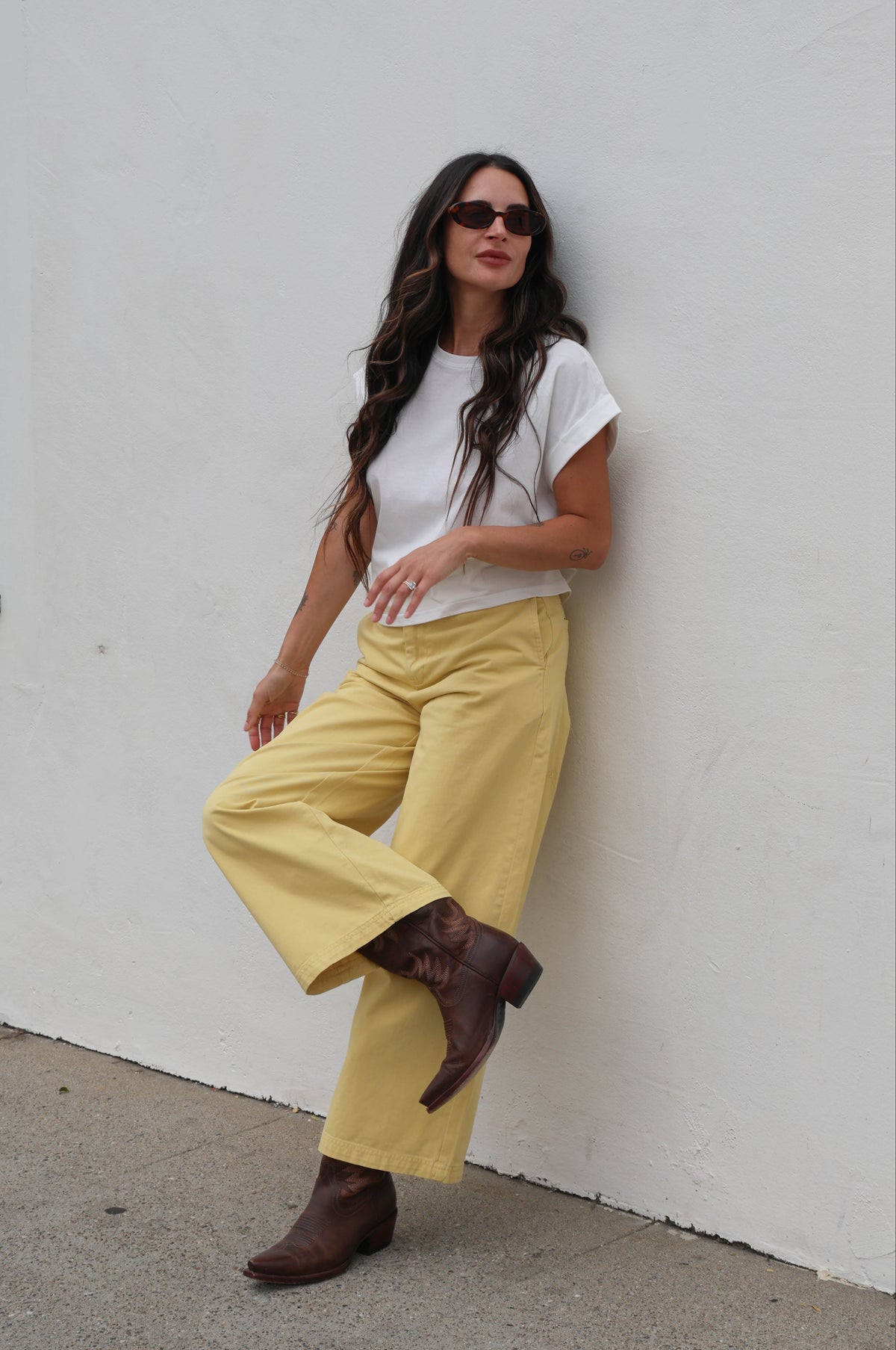 Woman wearing a white shirt with yellow trousers against a white background