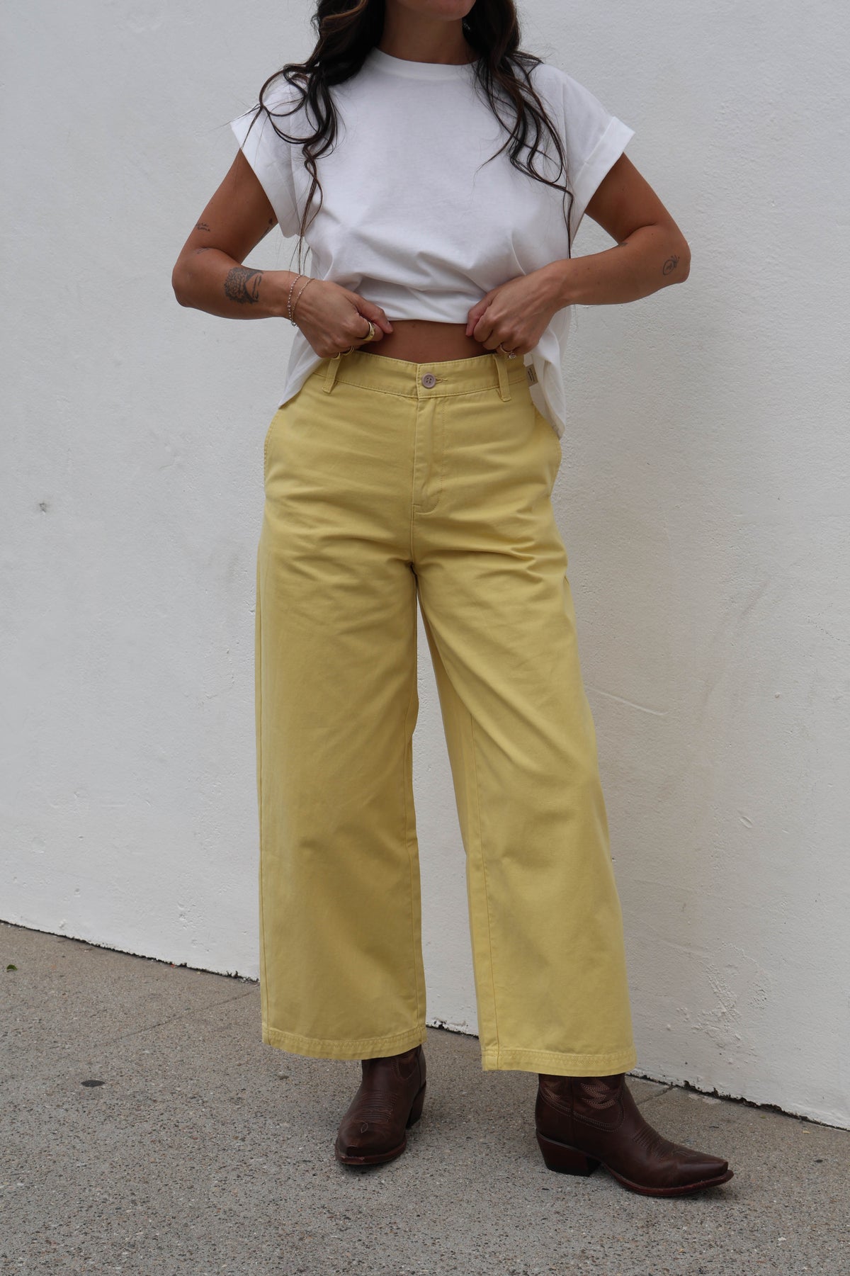 Woman wearing a white shirt with yellow trousers against a white background