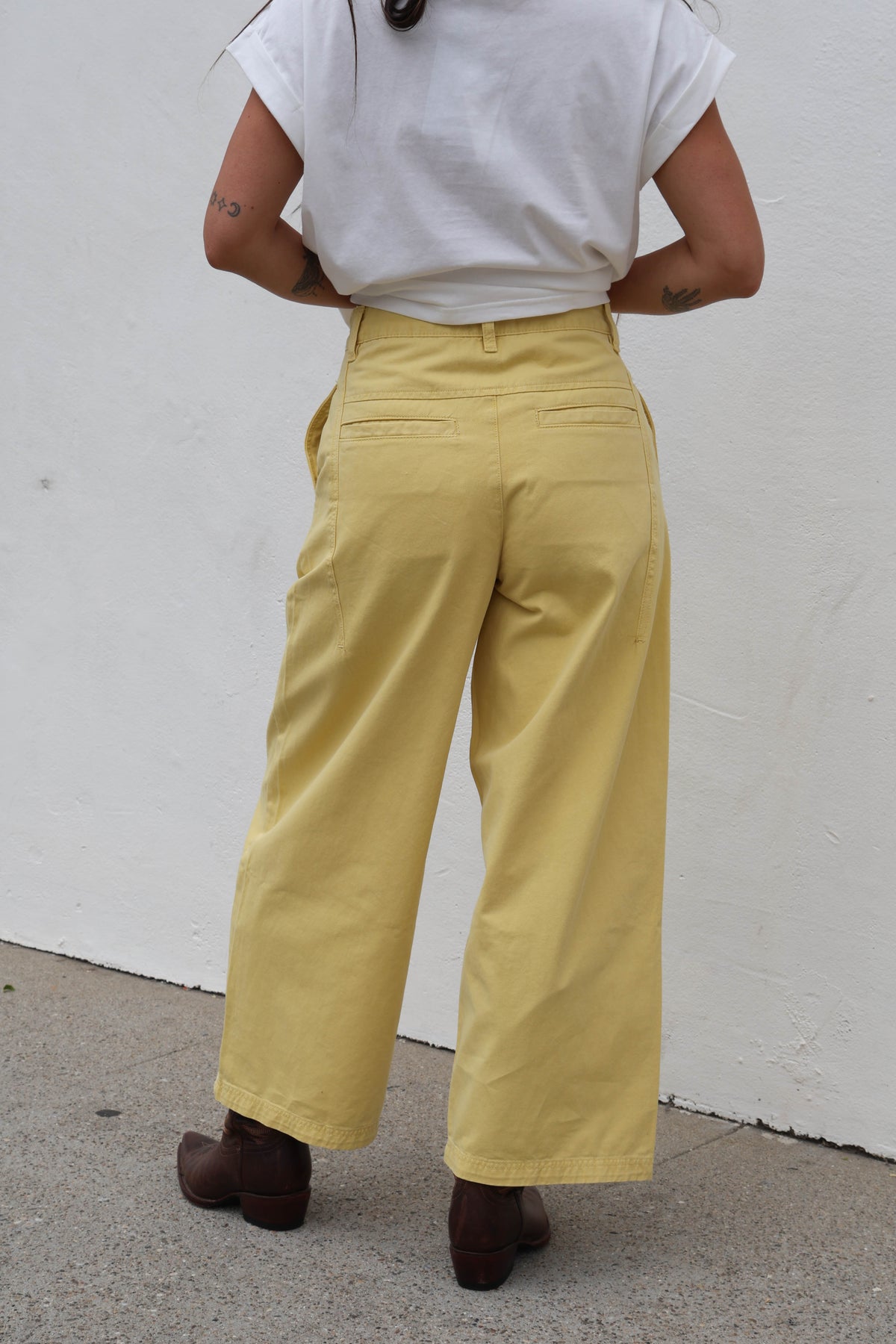Woman wearing a white shirt with yellow trousers against a white background