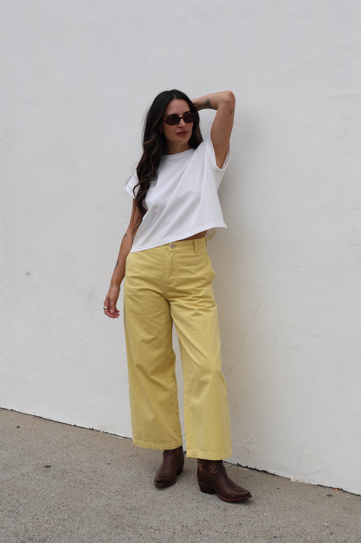 Woman wearing a white shirt with yellow trousers against a white background