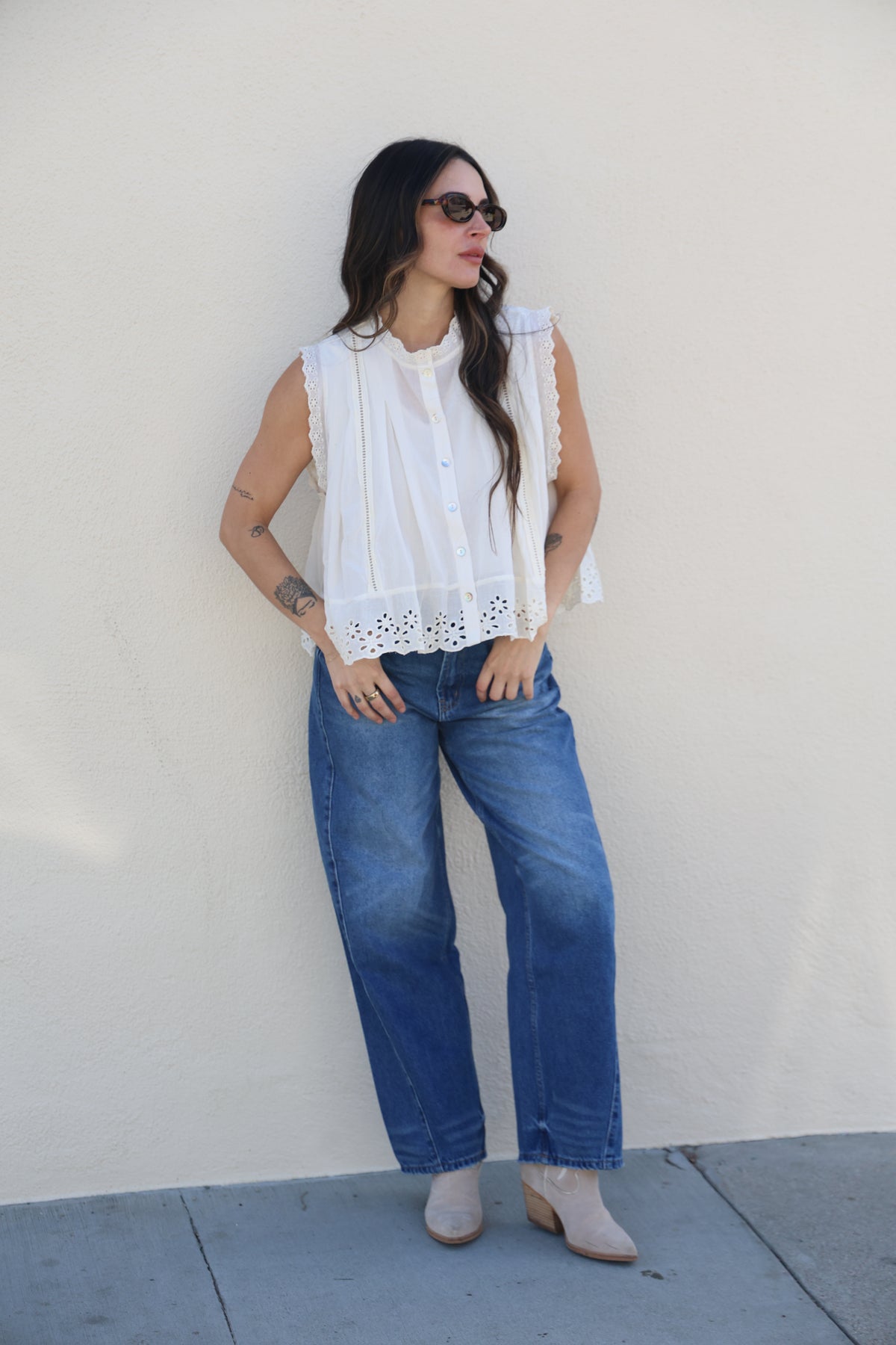 Woman wearing a white blouse and blue jeans on a plain background