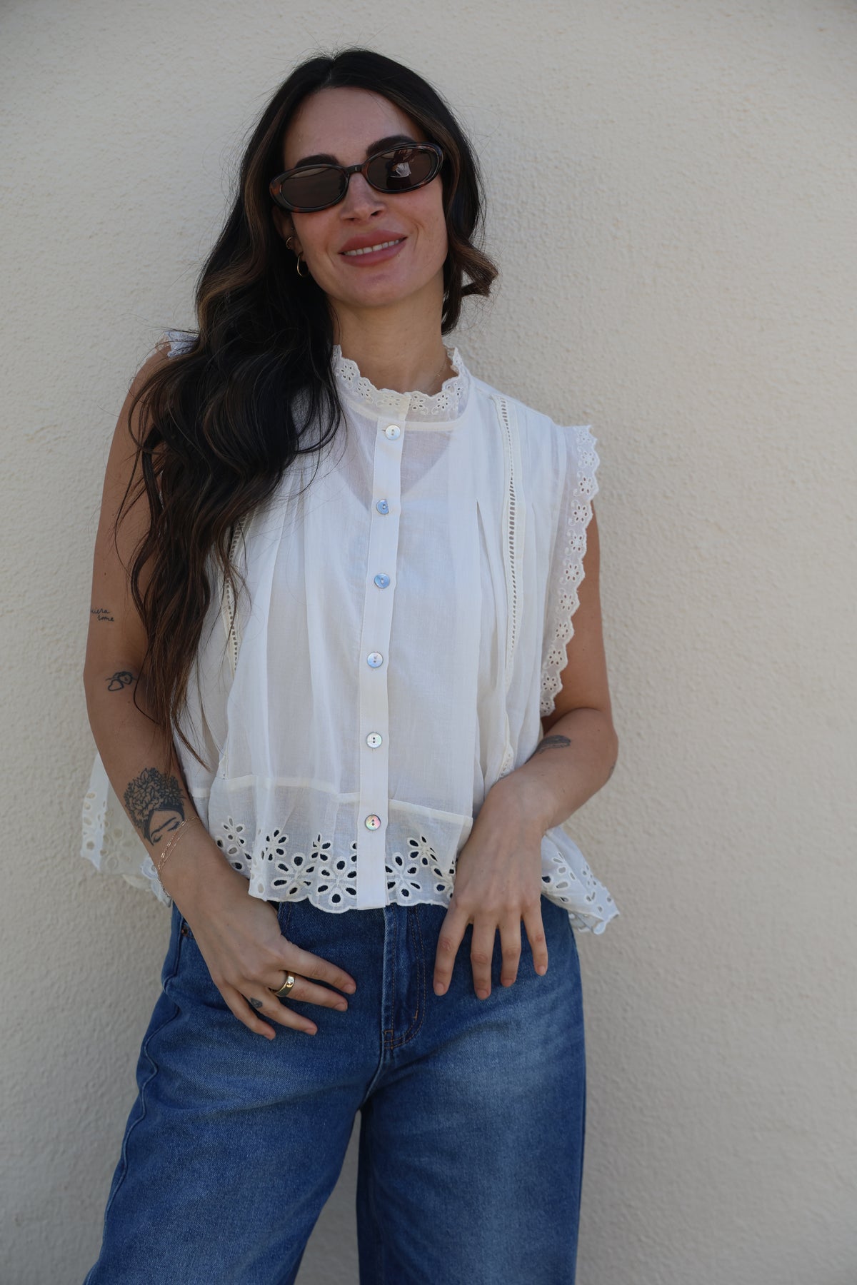 Person wearing a white blouse and blue jeans on a plain background