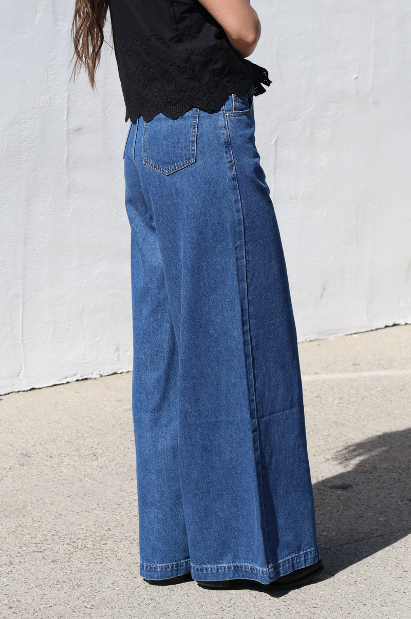 Person wearing blue jeans and a black top on a concrete surface