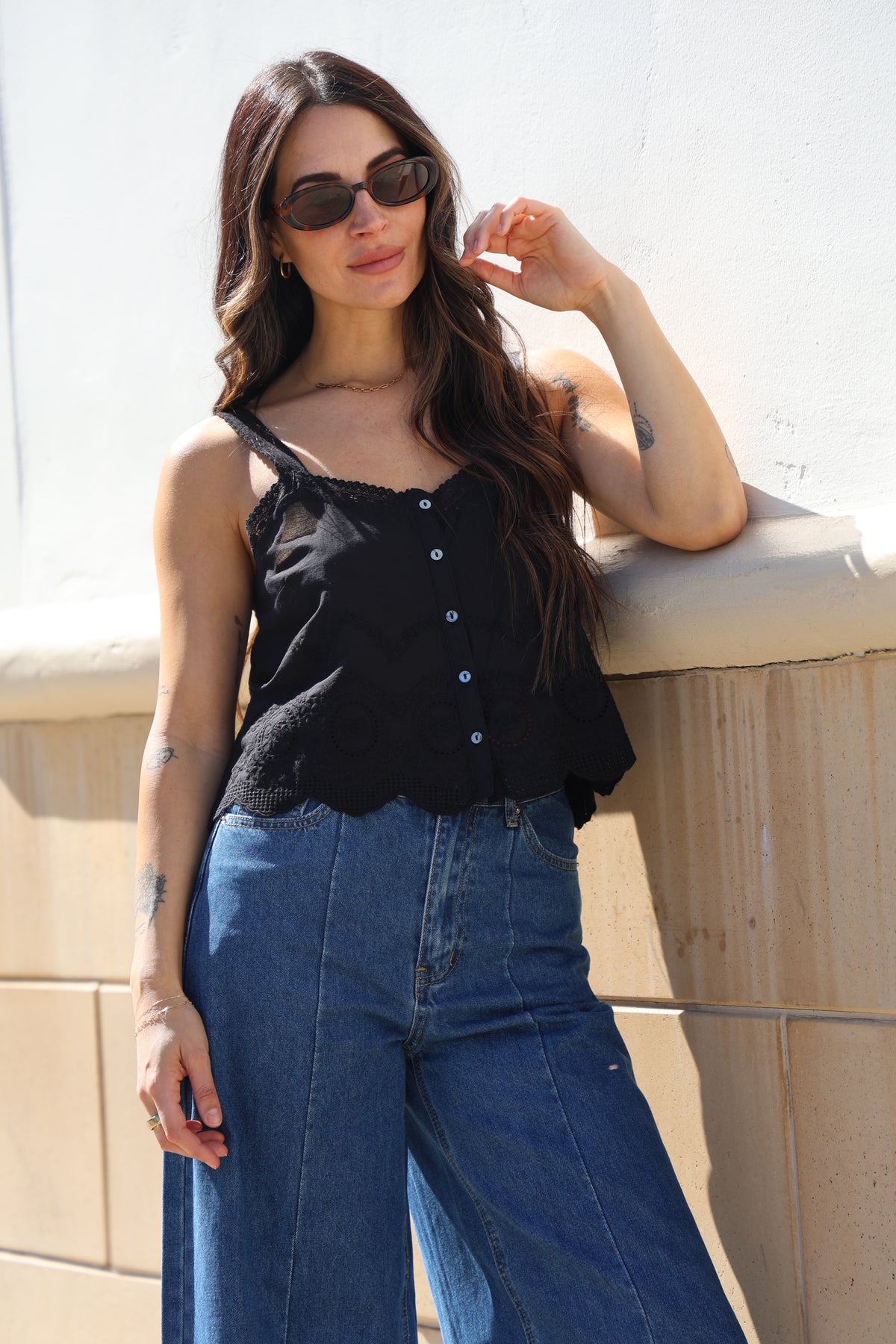 Woman lying on a wooden floor wearing sunglasses and a black top.