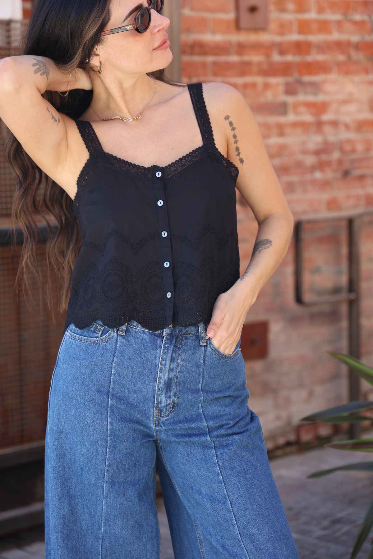Person wearing a black sleeveless top and blue jeans with a blurred background