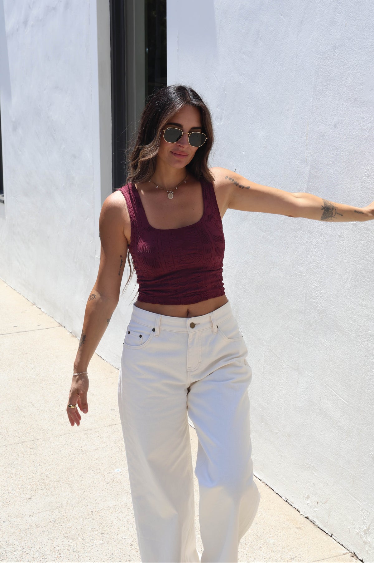 Woman wearing a maroon tank against a white wall
