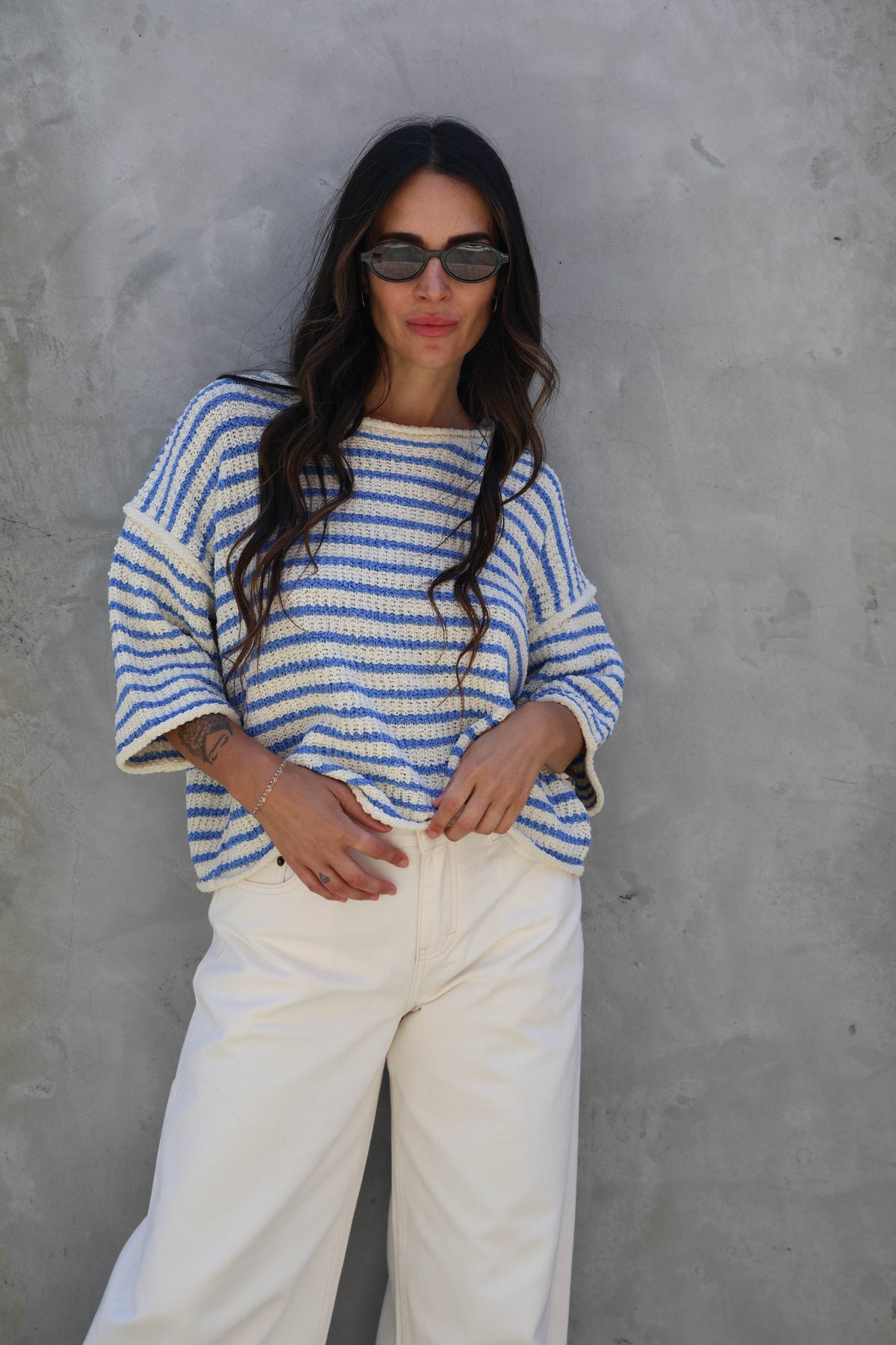 Woman wearing a striped short sleeve knit against a grey wall