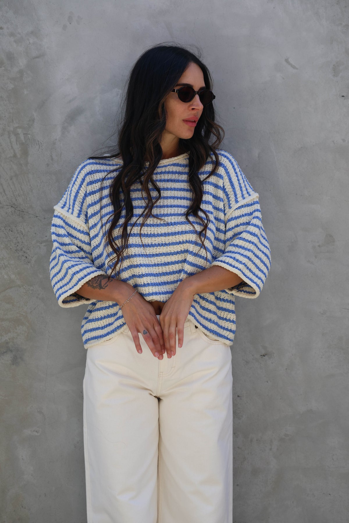 Woman wearing a striped short sleeve knit against a grey wall