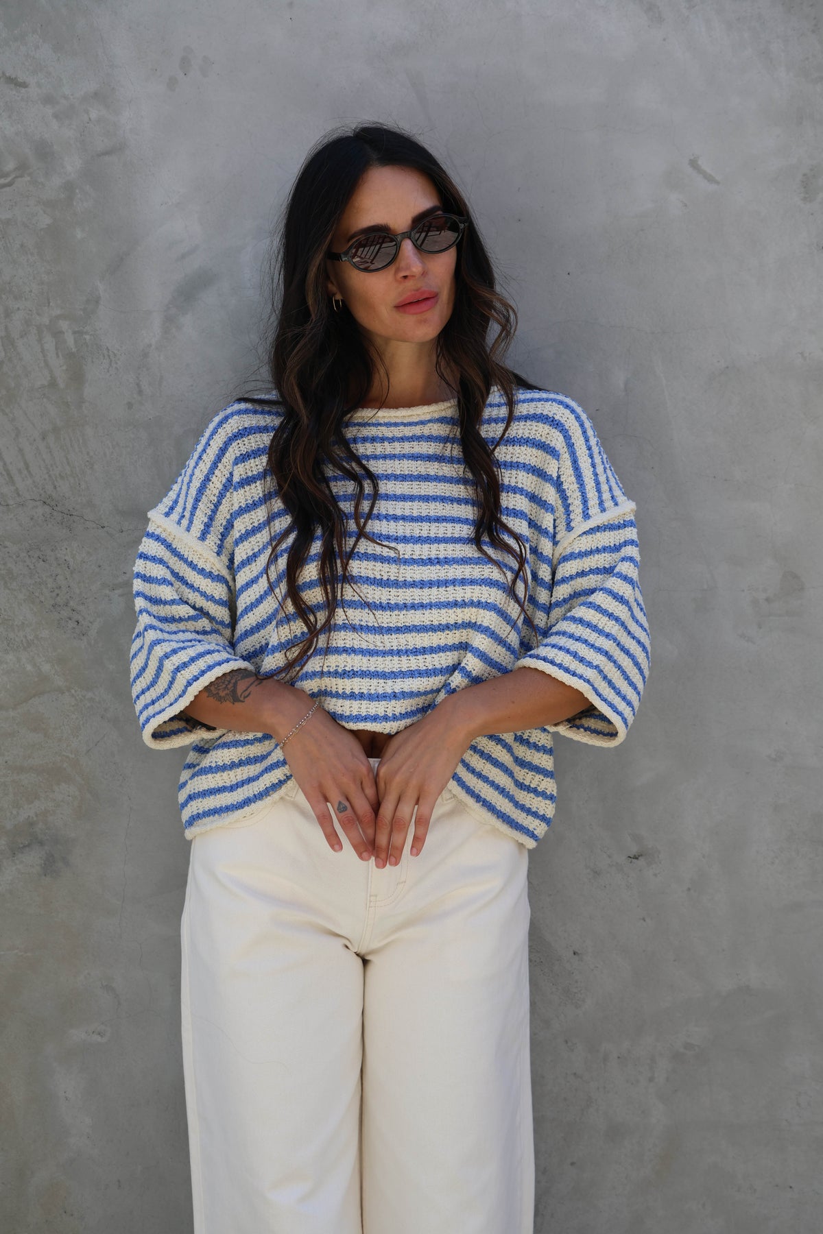 Woman wearing a striped short sleeve knit against a grey wall