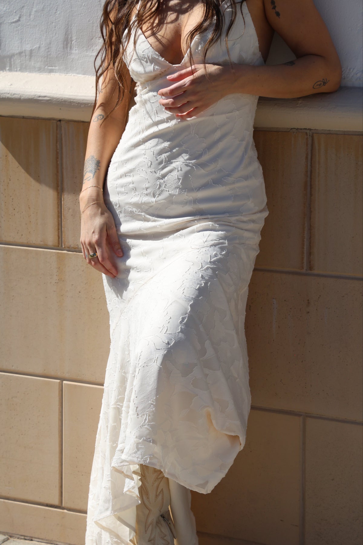 Person in a white dress with a beige tiled wall in the background