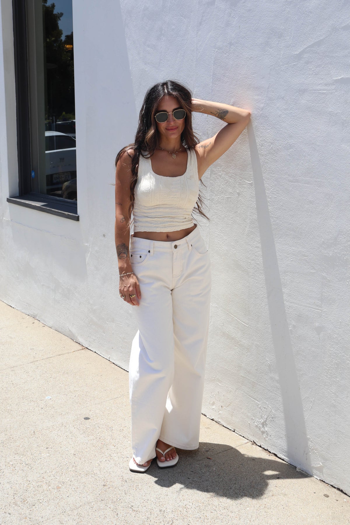 Woman wearing a butter cream tank against a white wall