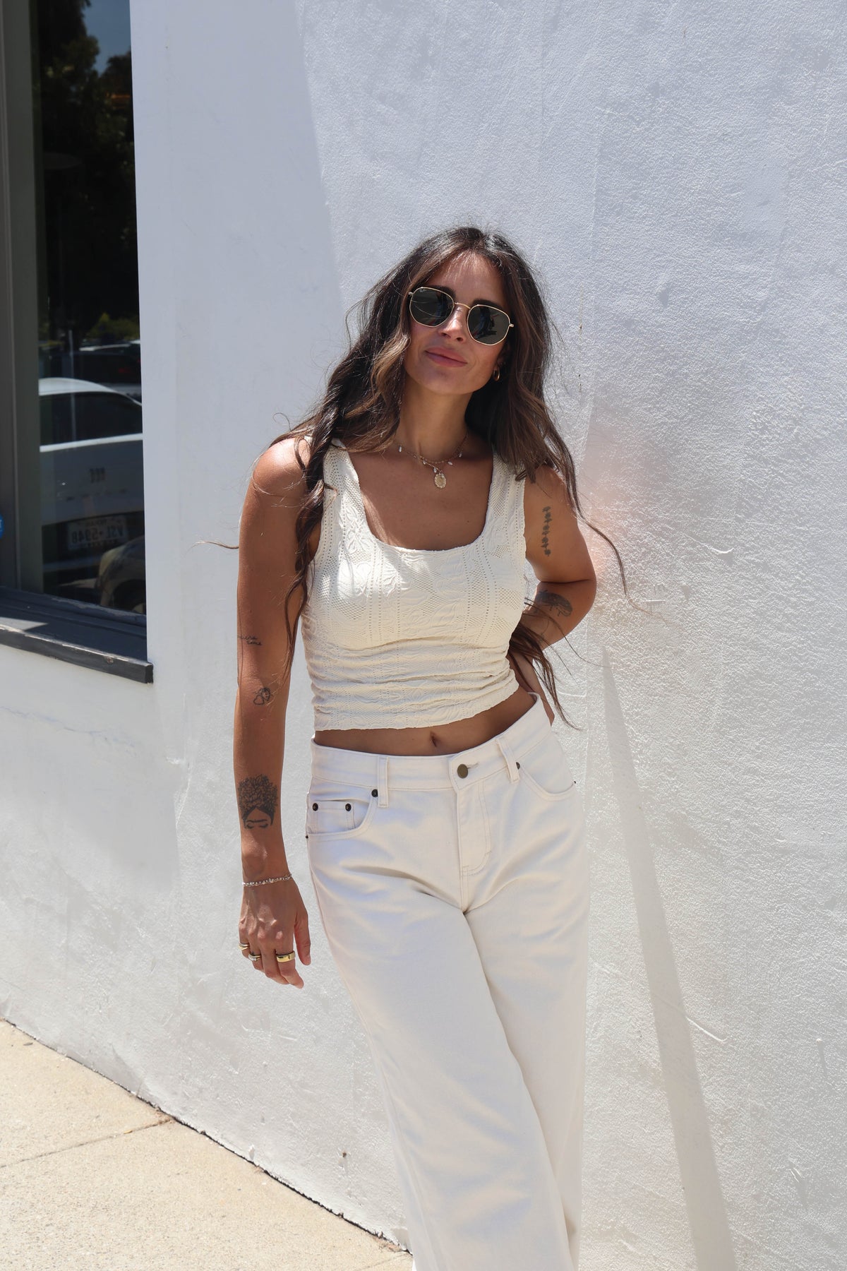 Woman wearing a butter cream tank against a white wall