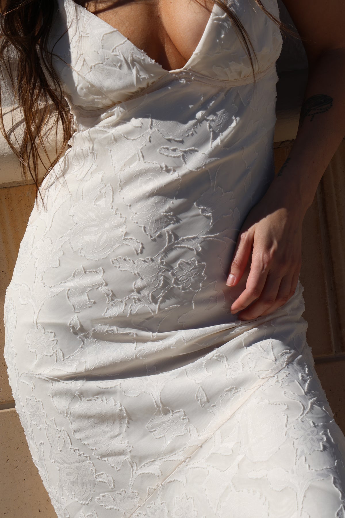 Person wearing a white lace dress with a close-up of the fabric texture.