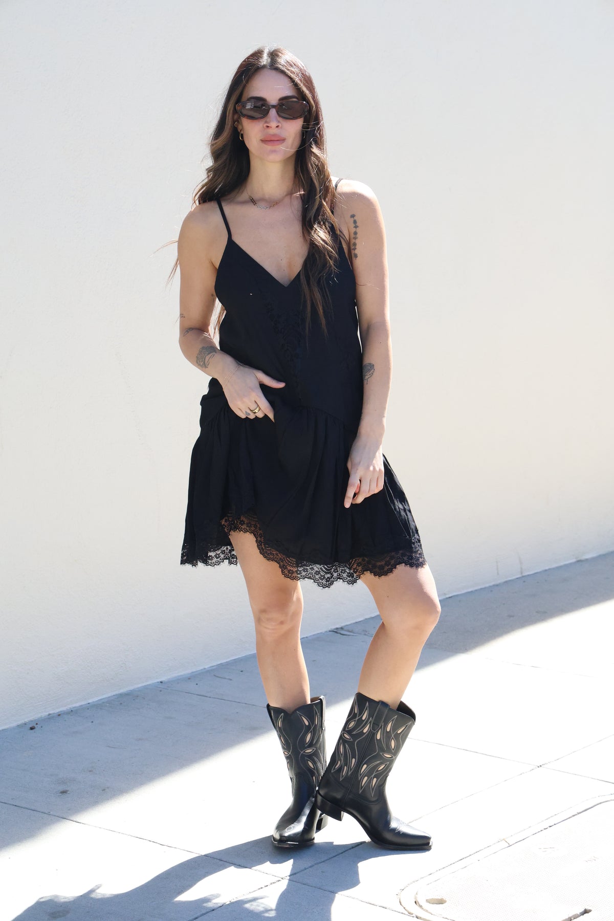 Woman in a black dress and boots standing on a white background