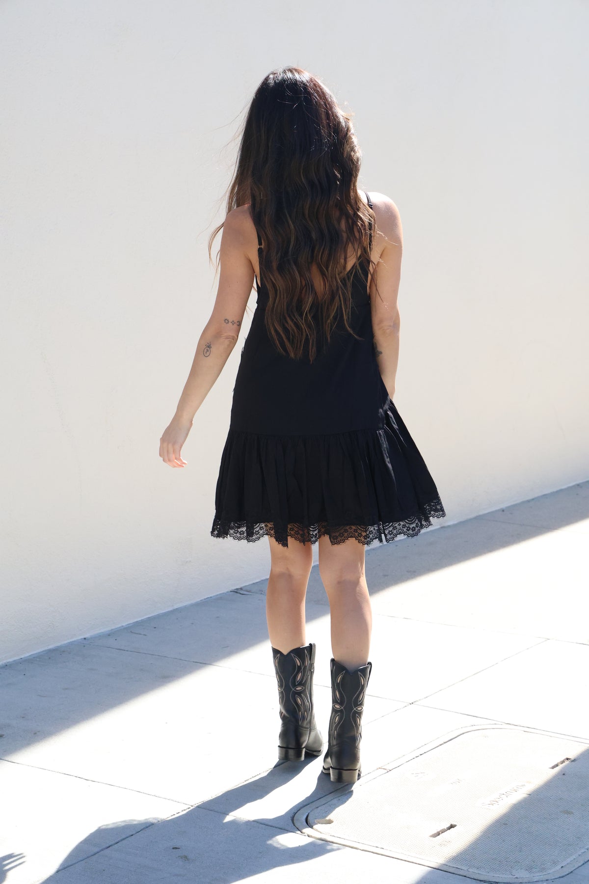 Person wearing a black dress and boots on a white background