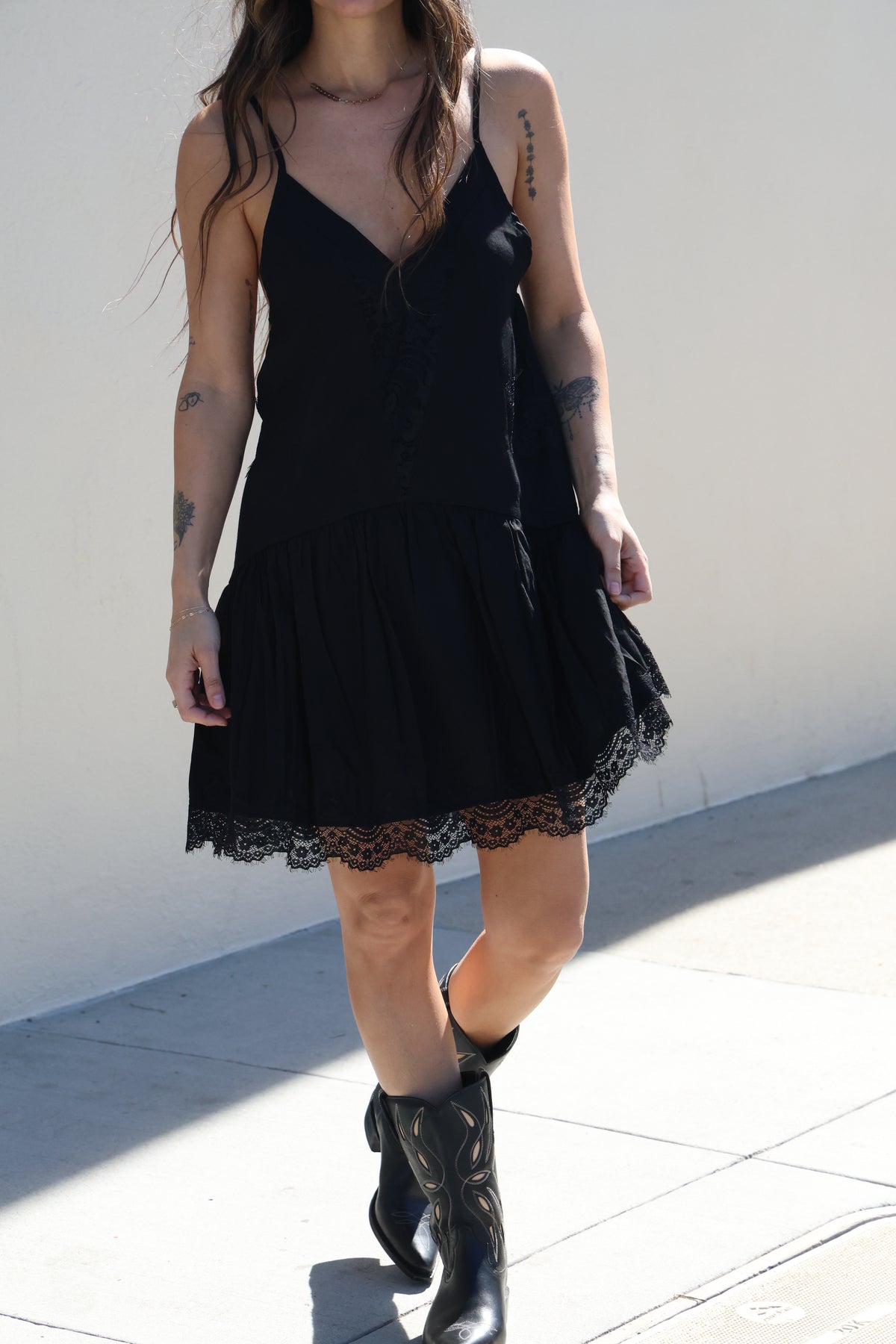 Person wearing a black dress with lace details on a white background