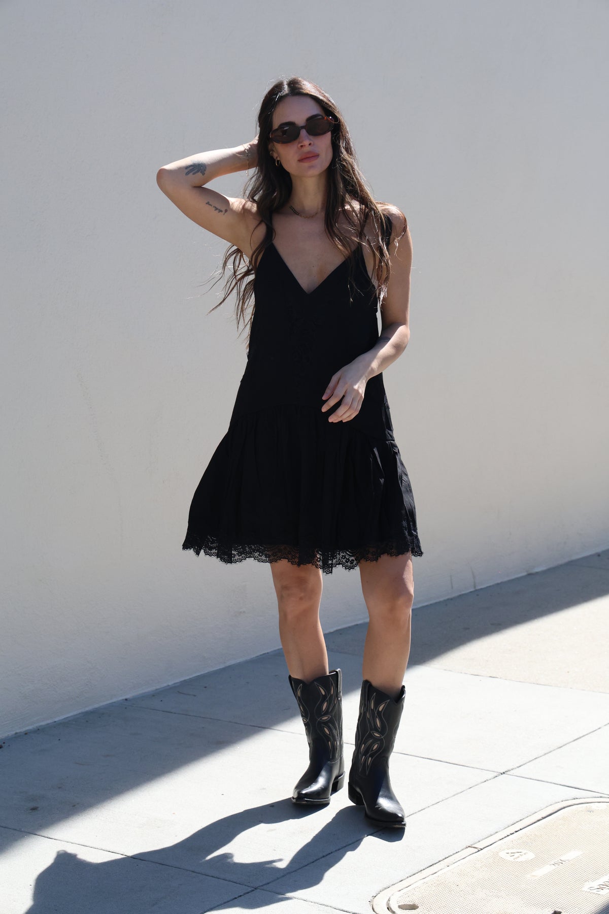 Woman in a black dress and boots standing on a white surface
