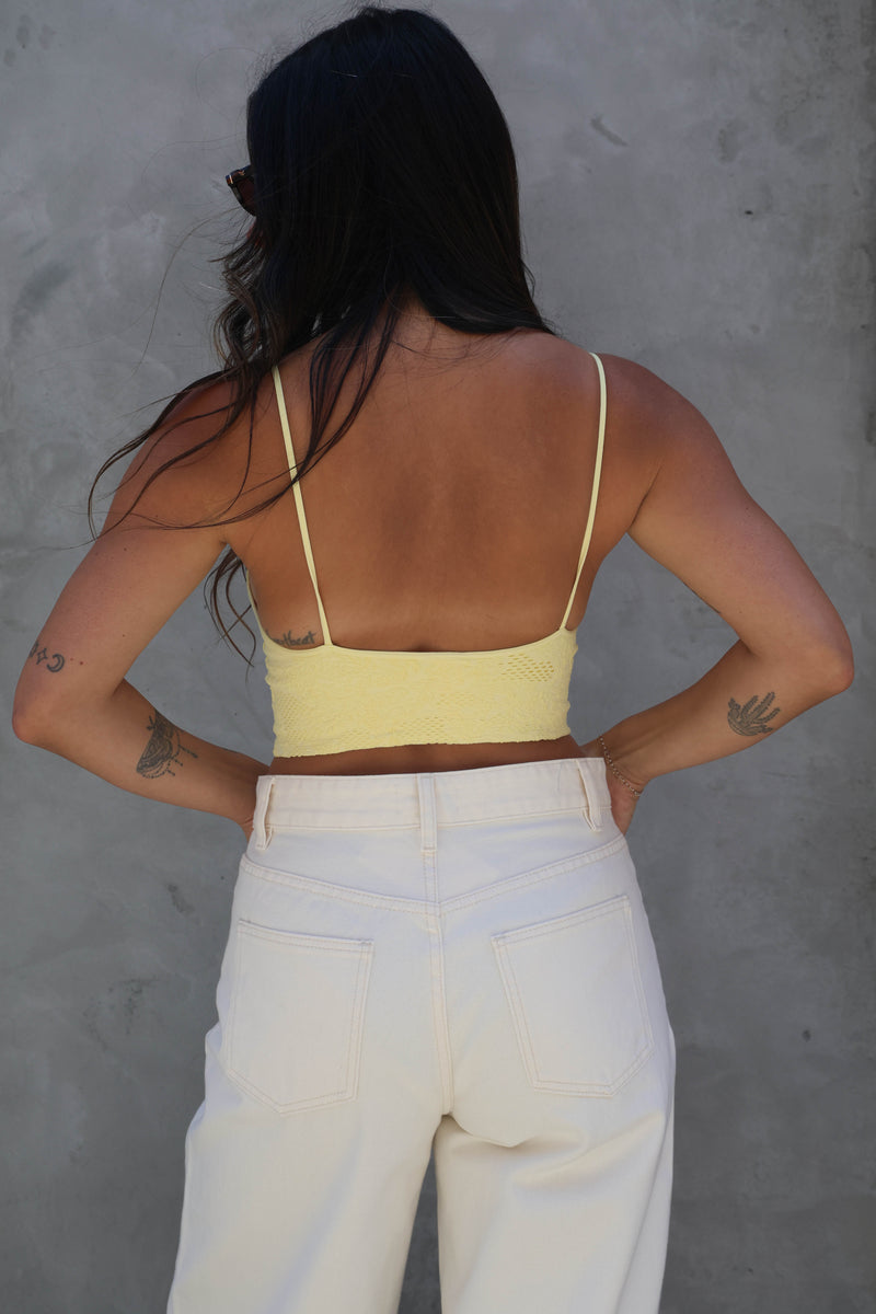 Person wearing a yellow top and white pants against a gray background