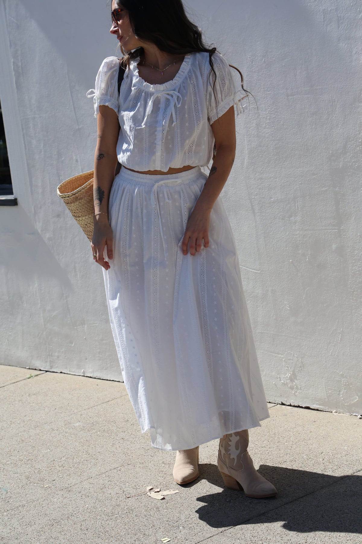 Person wearing a white dress standing on a concrete surface.
