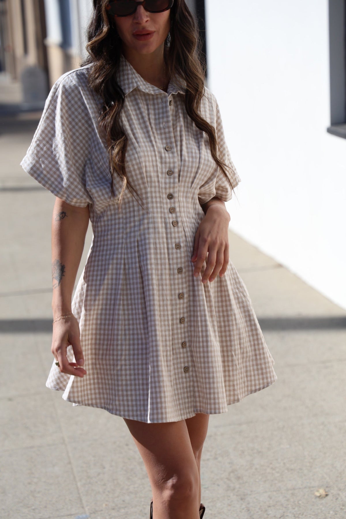 Woman wearing a checkered dress on a sidewalk