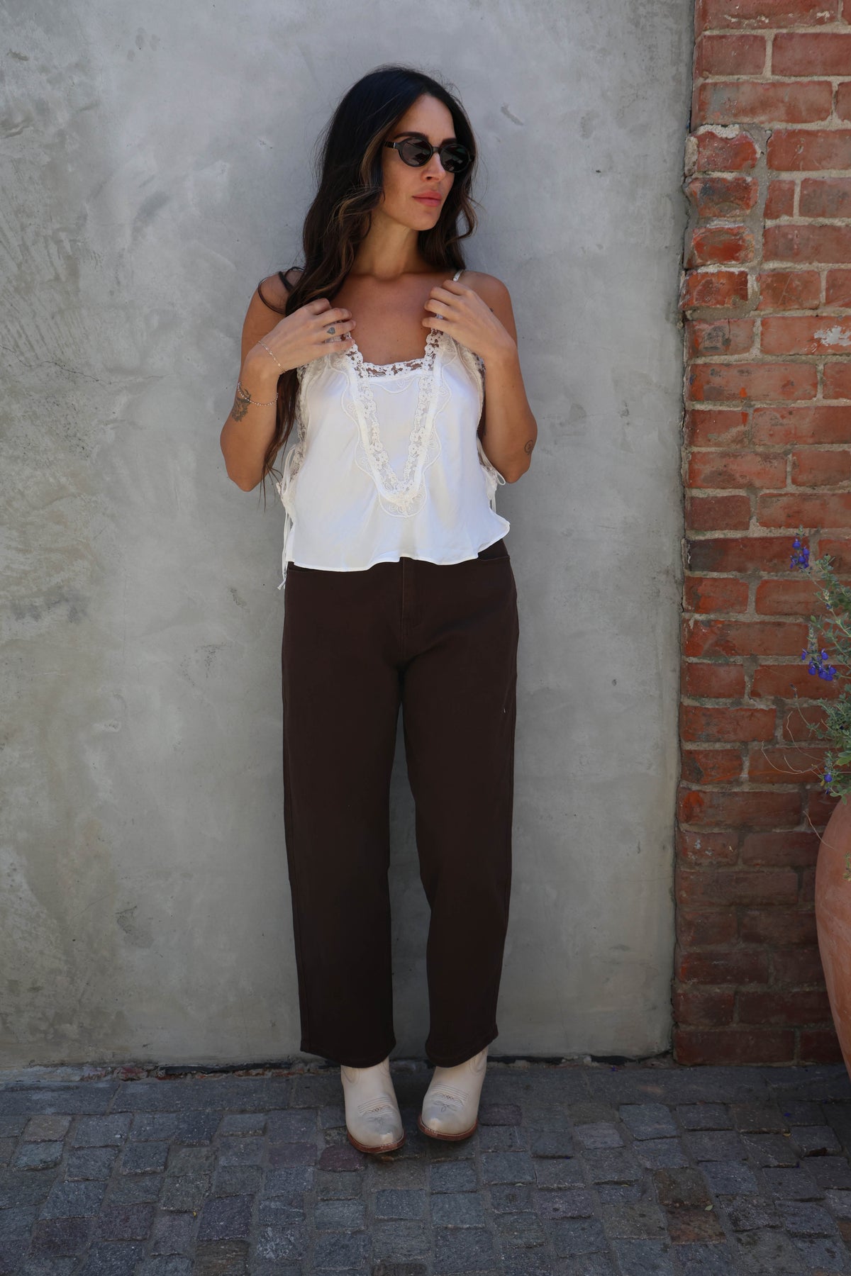 Woman wearing a white delicate lace tank in front of a grey wall