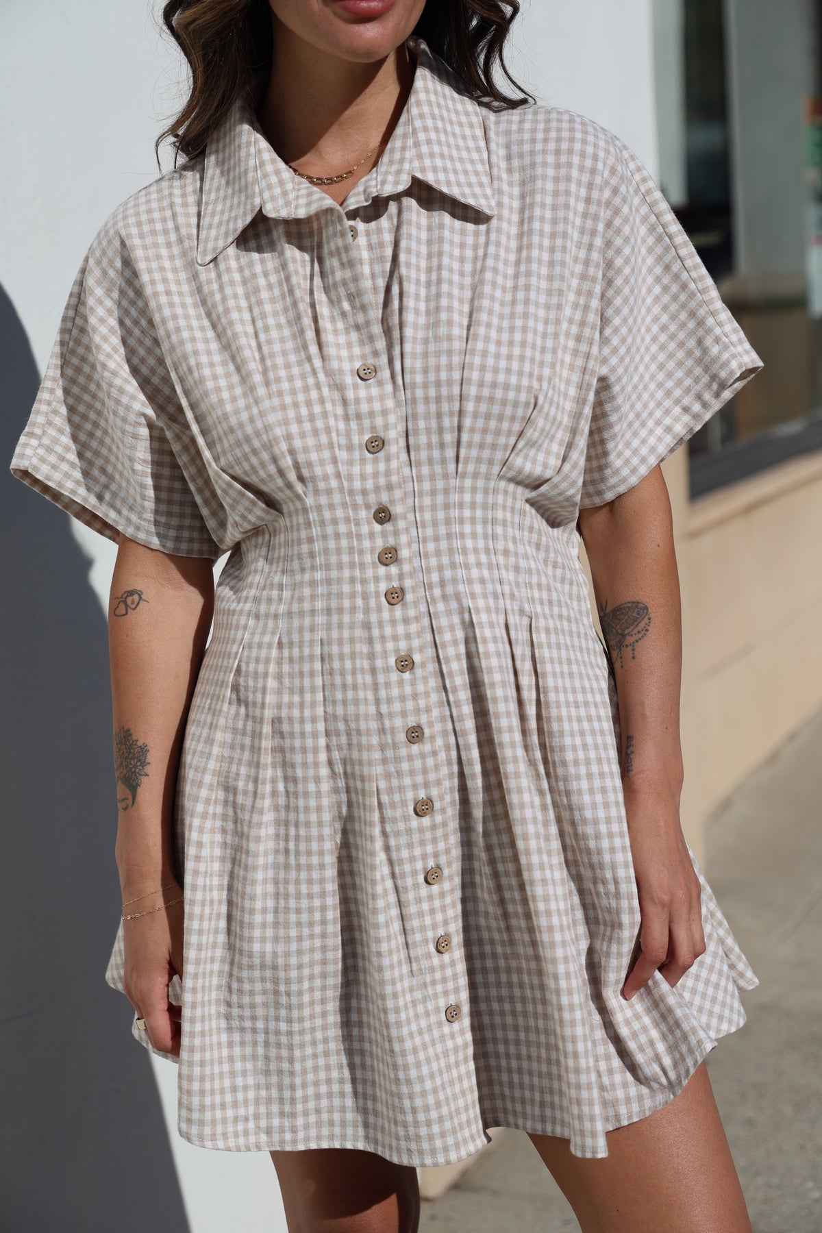 Woman wearing a checkered dress with short sleeves and buttons on a blurred background